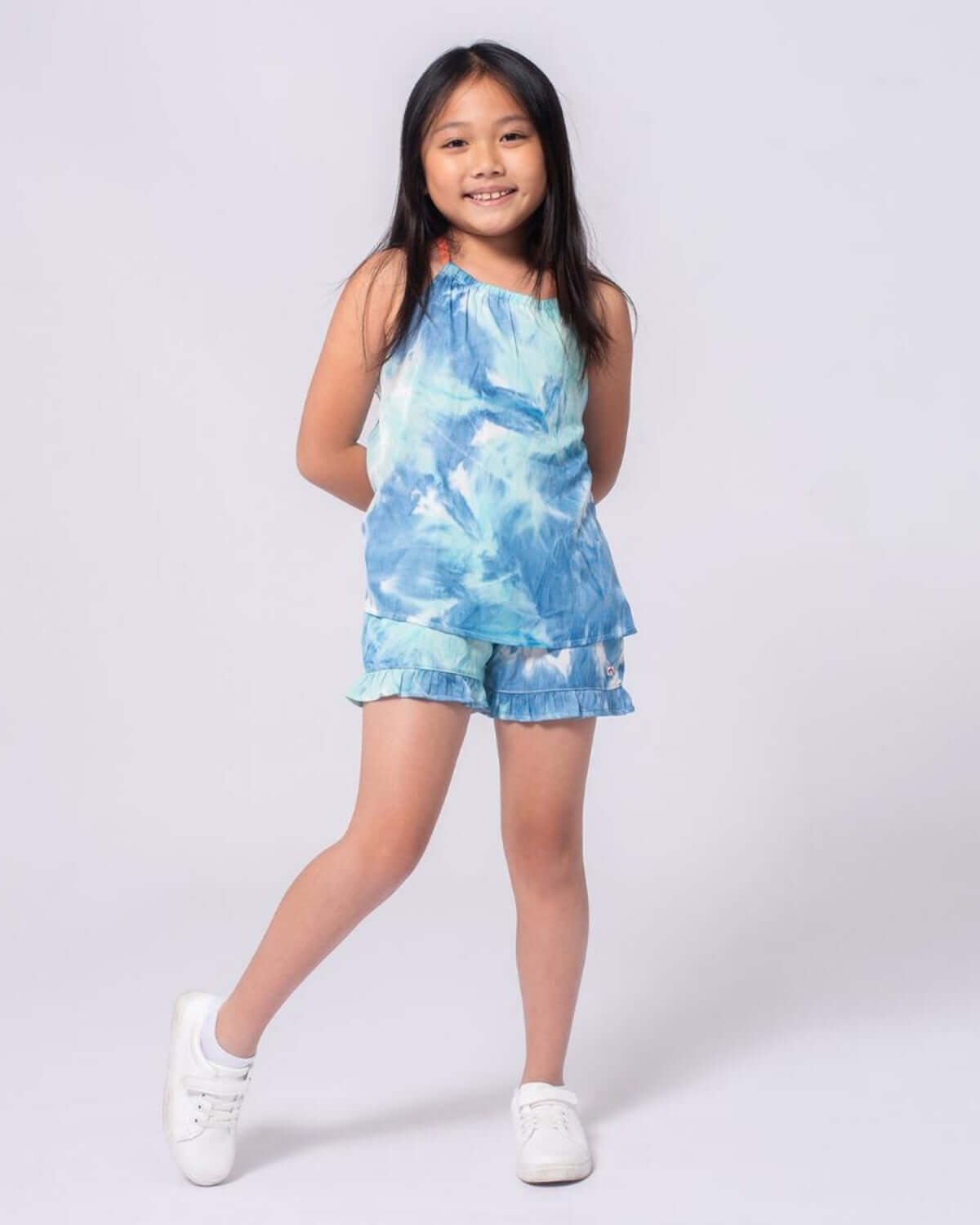 A young girl wearing the Turquoise Water Sanibel Tank paired with matching shorts, perfect for summer play.