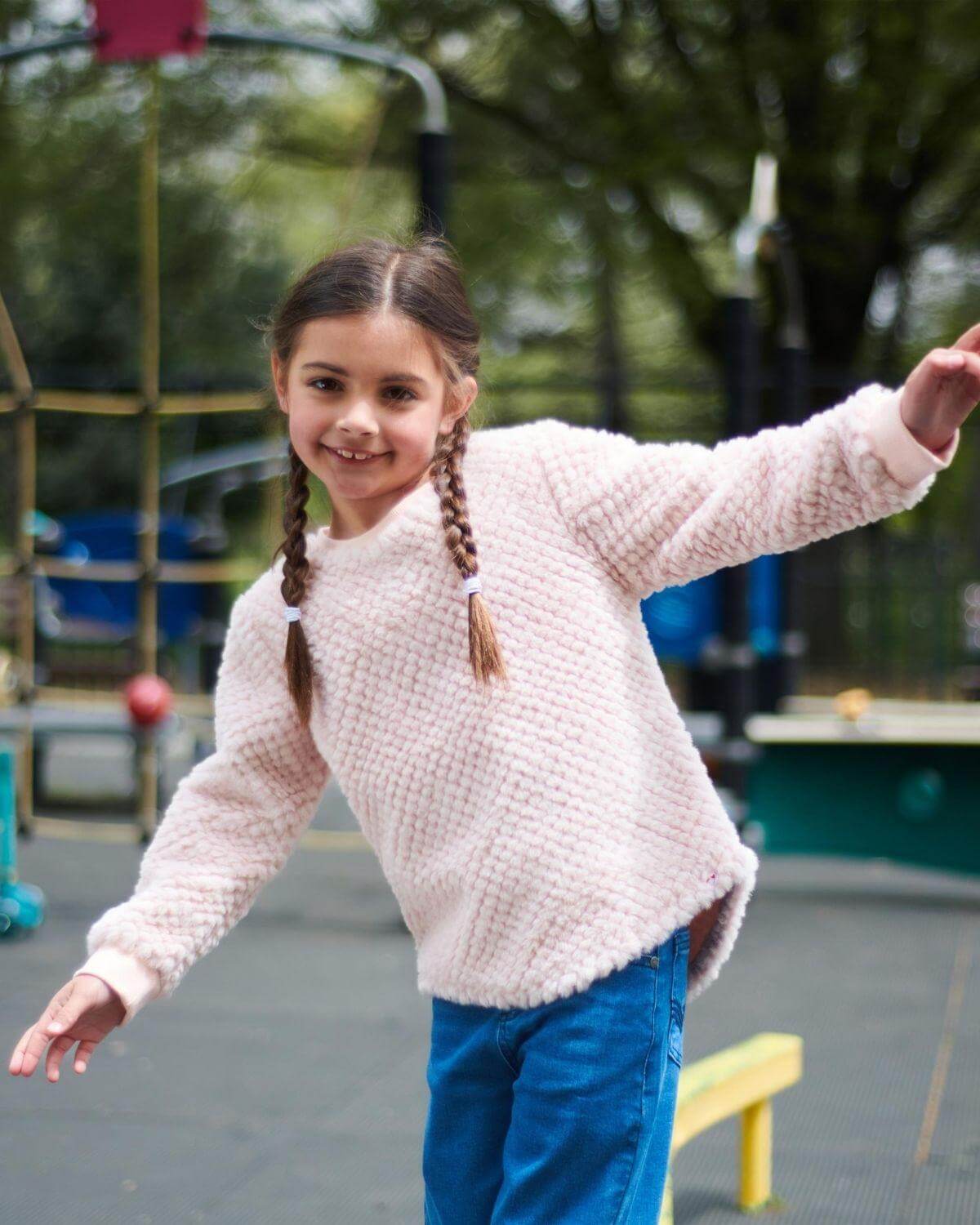Joyful girl in pink faux fur top, embracing fun at the playground. Stylish kids clothes for a cozy fall adventure!