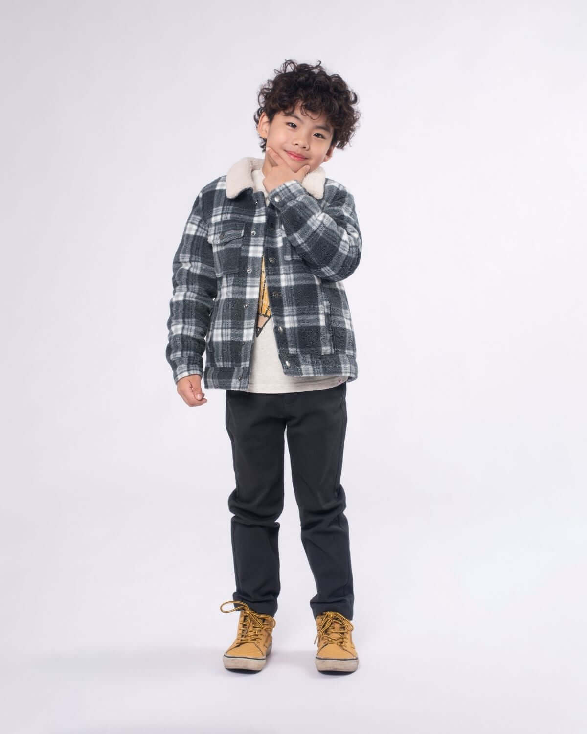 Stylish kid in a grey buffalo check jacket with Sherpa lining, perfect for back to school adventures in cozy comfort.