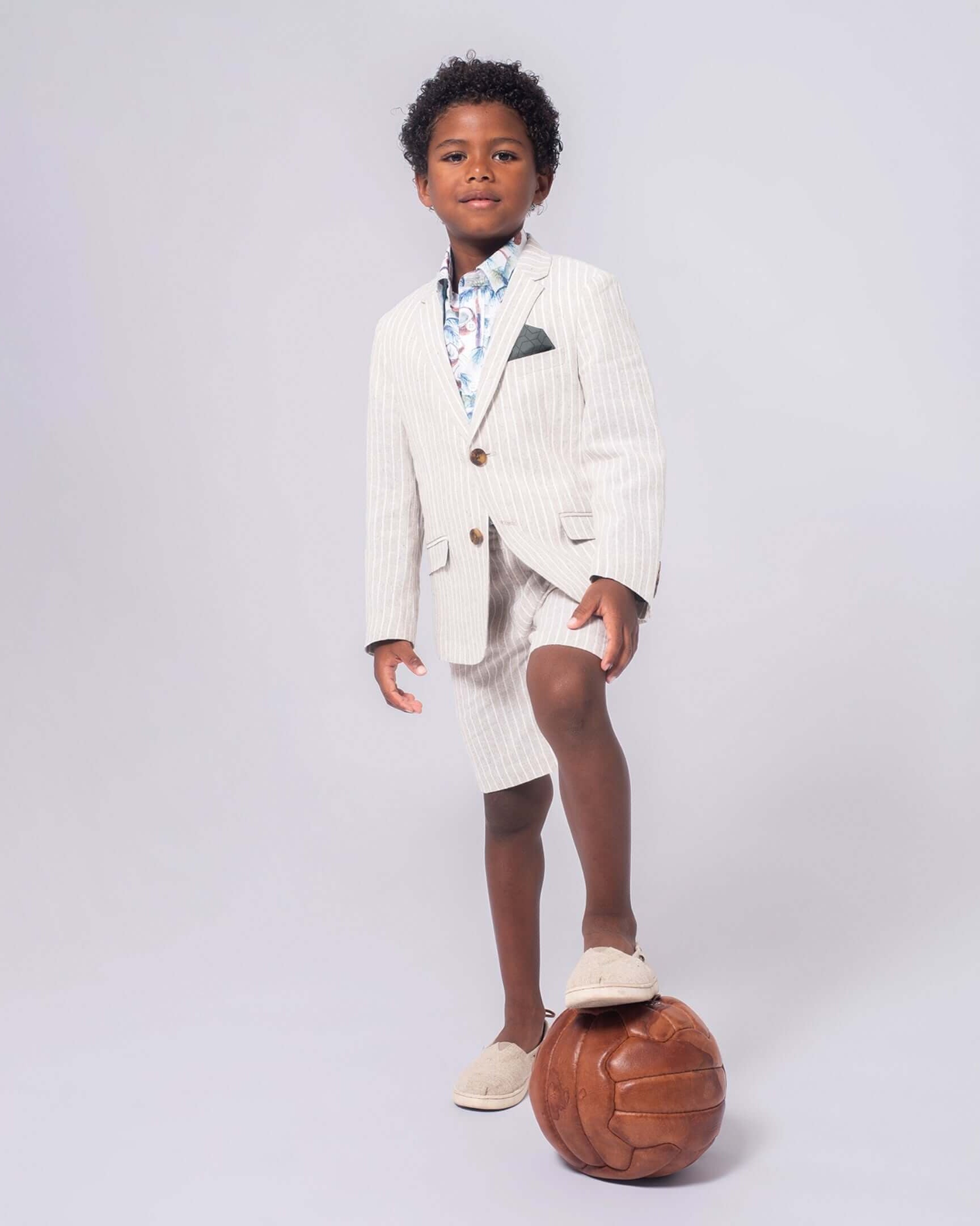 Stylish young boy sports a sand stripe linen short suit, rocking confidence and comfort for sunny days and back to school fun!