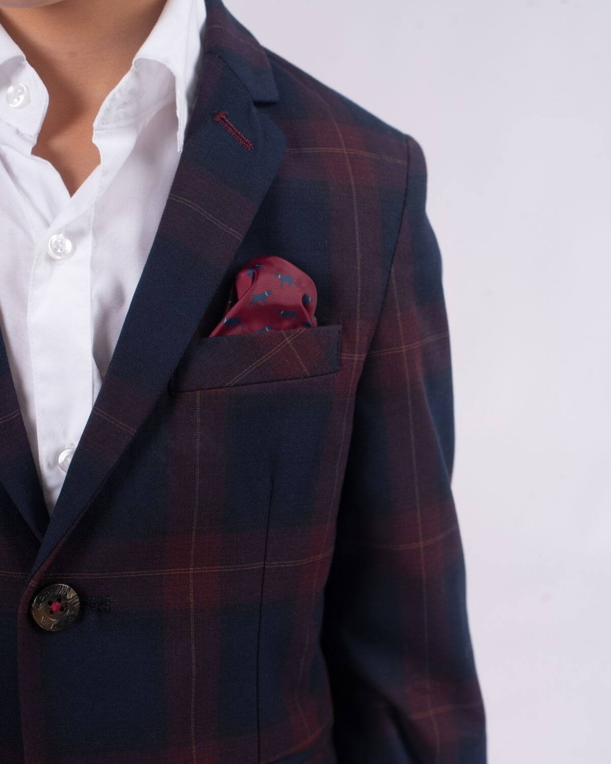 Stylish boy in Navy/Cranberry plaid suit, showcasing a playful pocket square and dapper white shirt for school or special events.