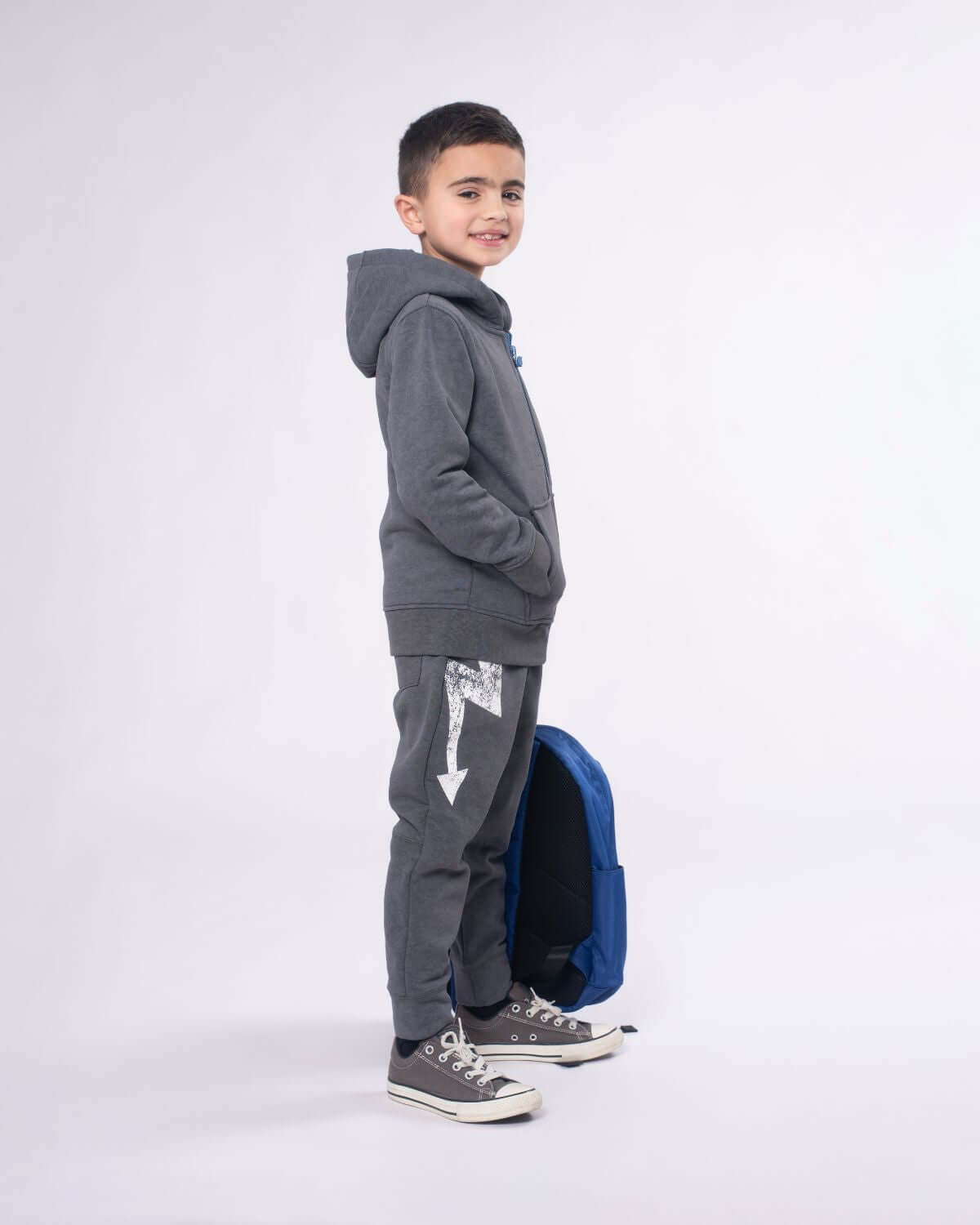 Happy kid in a washed grey hoodie with a backpack, showcasing laid-back style for school and play.