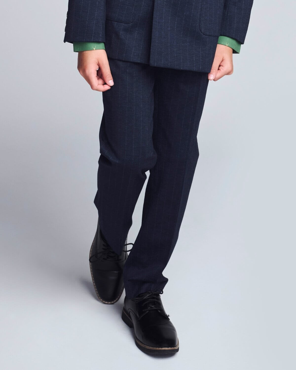 Person wearing a dark suit with green shirt cuffs on a light gray background
