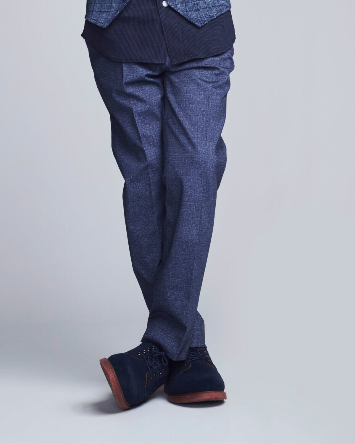 Person wearing a blue suit with matching shoes on a light gray background