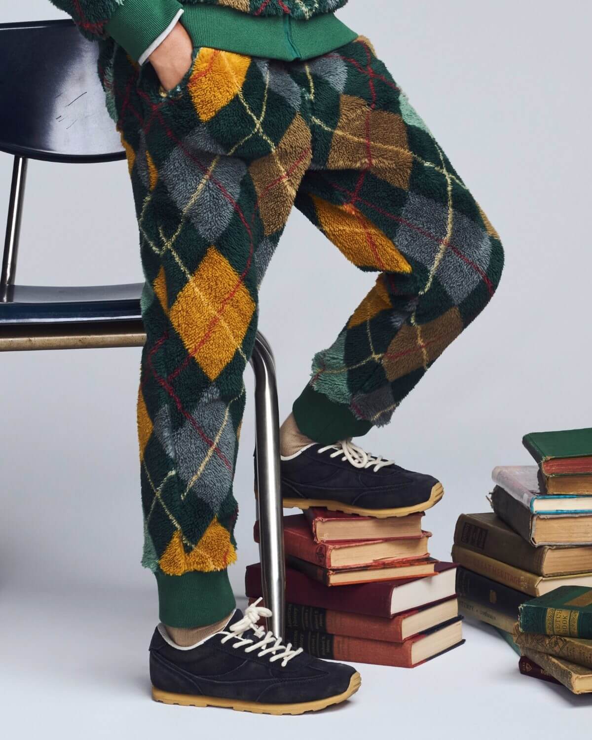 Person wearing argyle patterned pants and black shoes standing on a stack of books.