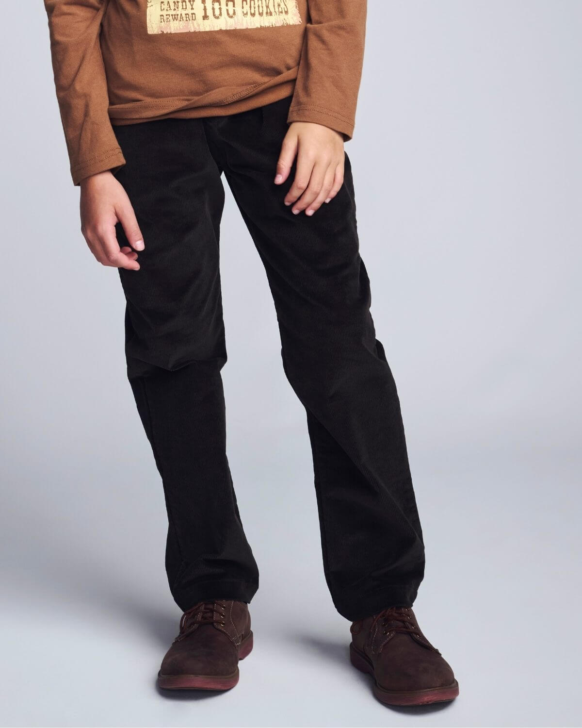 Person wearing black pants and brown shoes on a light gray background