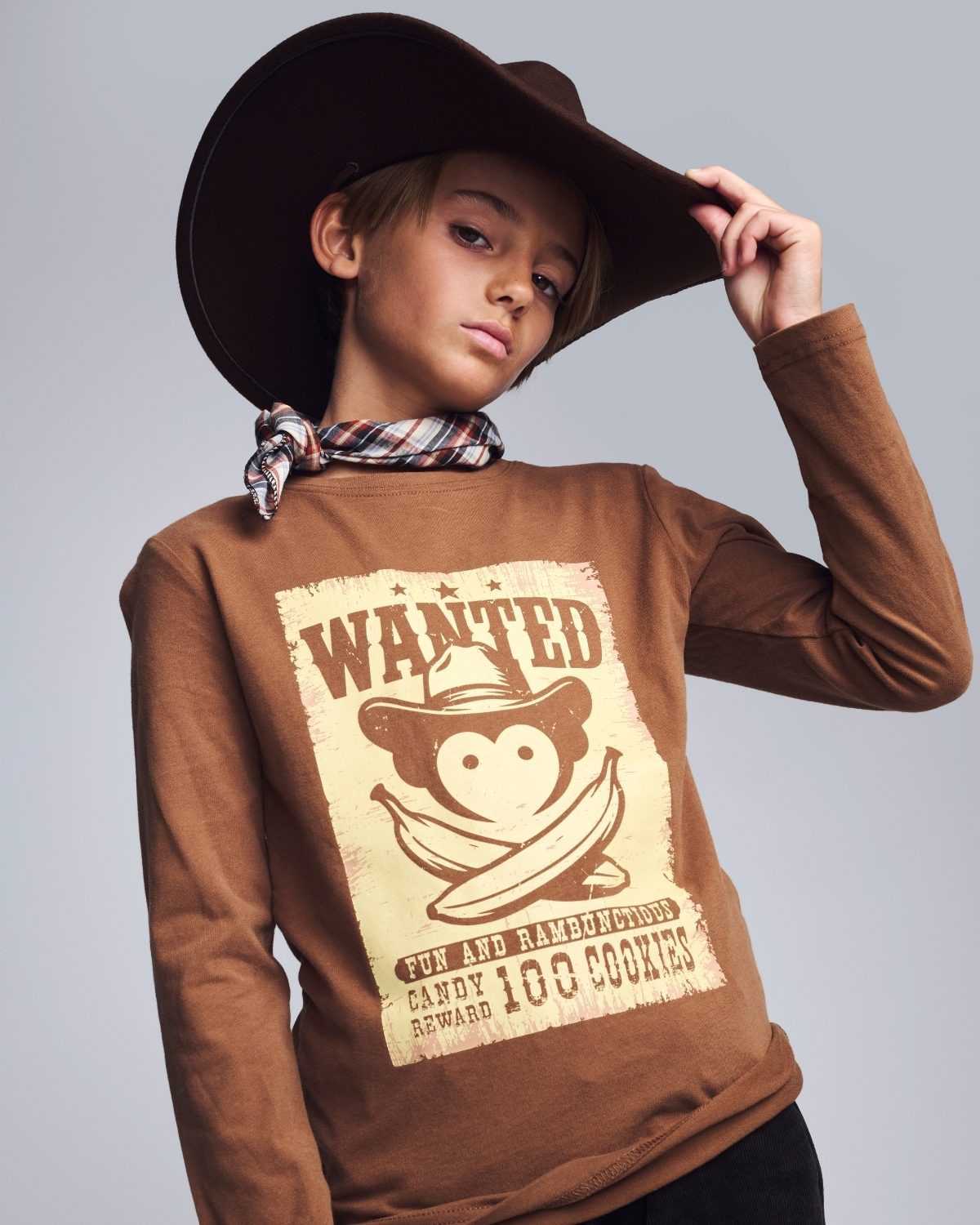 Person wearing a brown long-sleeve shirt with a 'Wanted' graphic design on a plain background