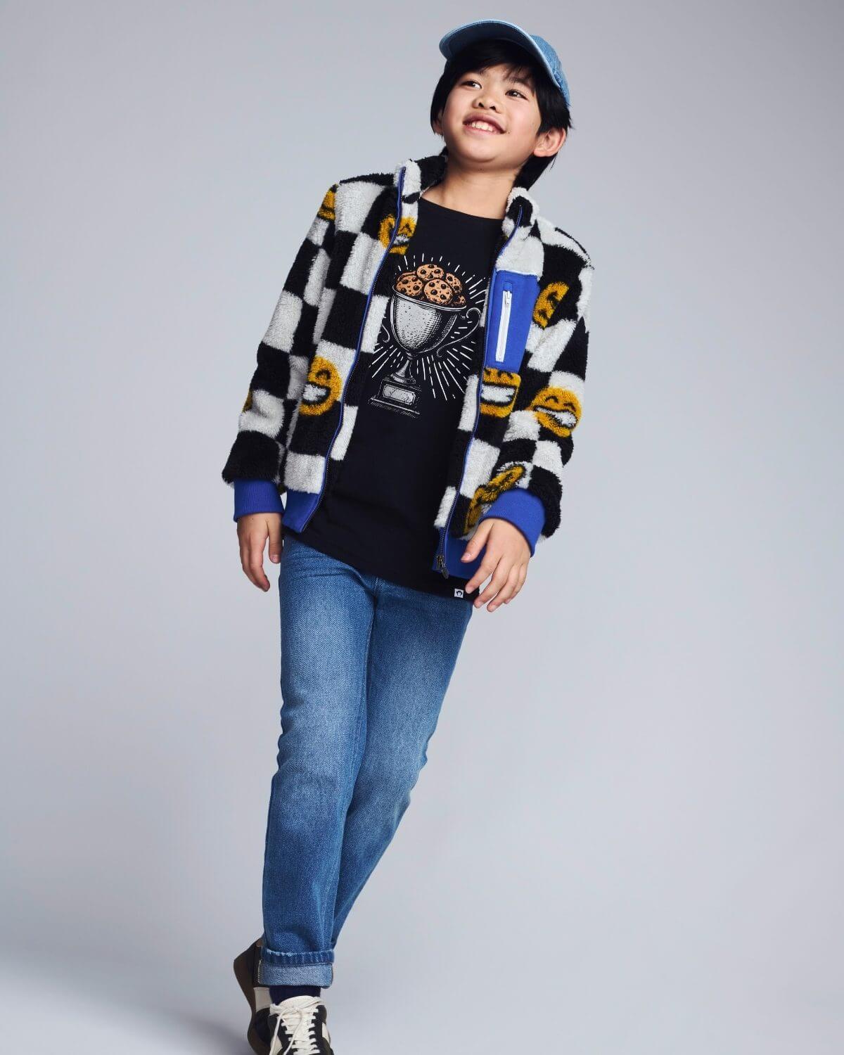Person wearing a checkered shirt, graphic t-shirt, and jeans on a plain background