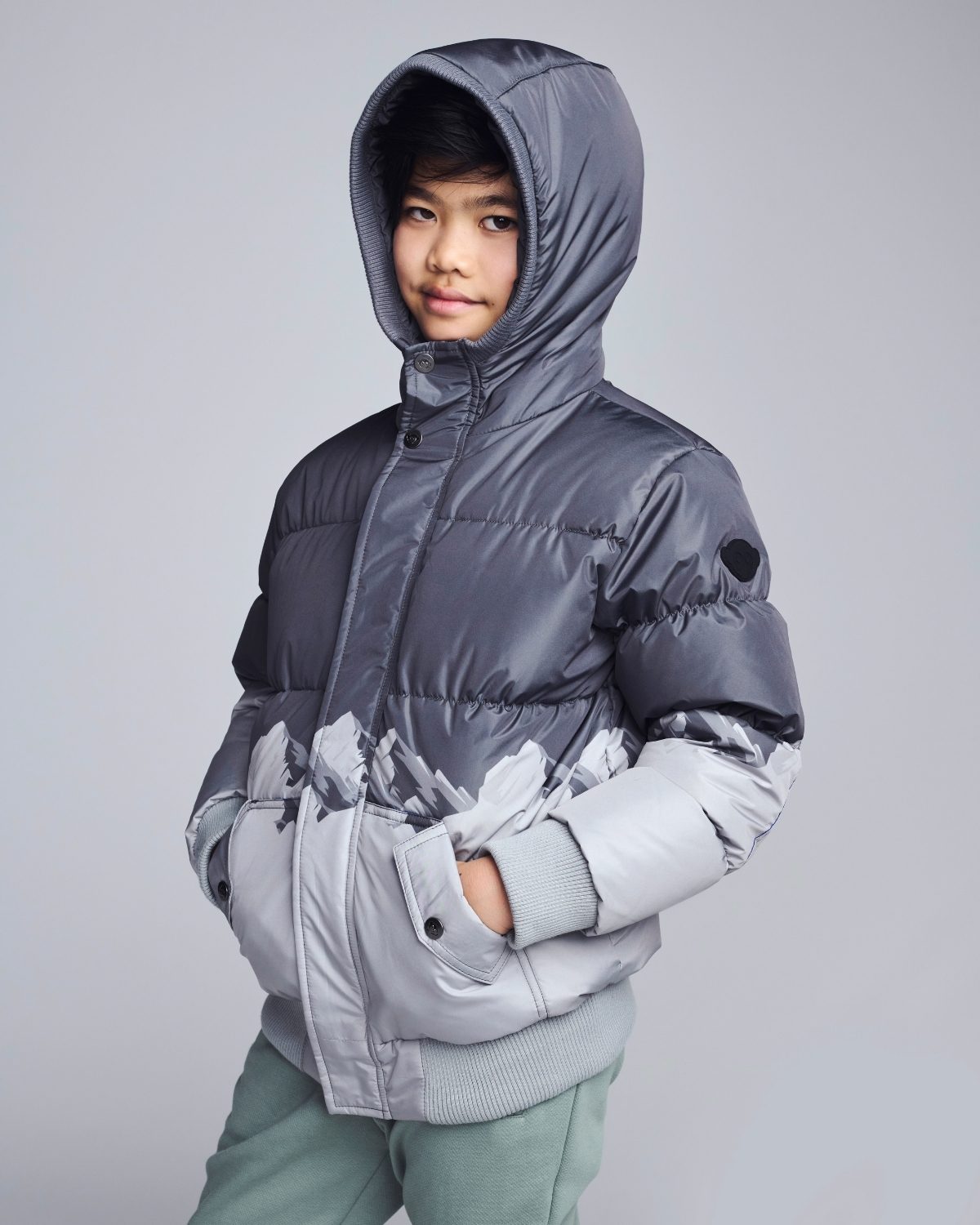 Person wearing a gray hooded jacket on a plain background