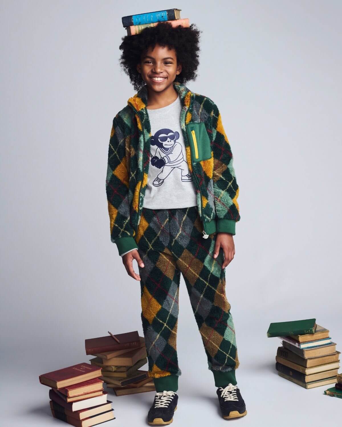 Child wearing a plaid outfit with books around them on a light gray background
