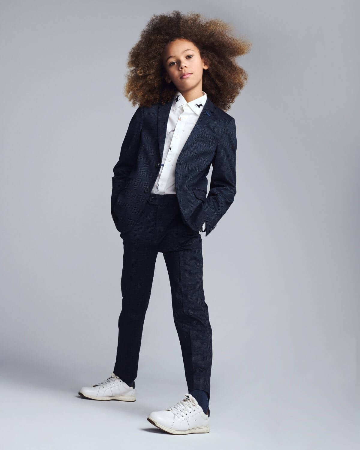 Child wearing a navy suit with a white shirt on a gray background