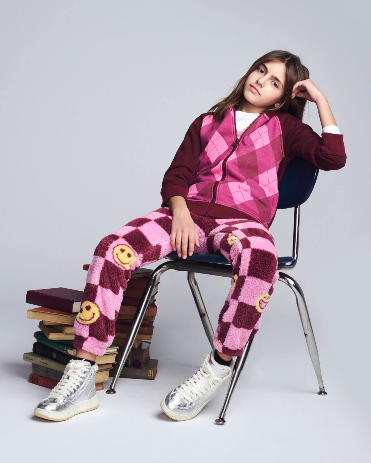 Person wearing a pink and purple checkered outfit with smiley face patterns, sitting on a chair.