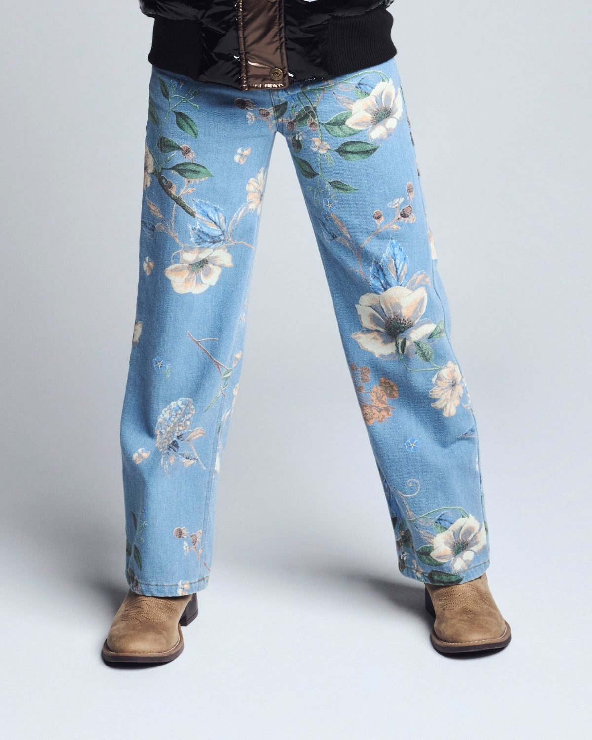 Light blue jeans with floral pattern worn by a person on a white background