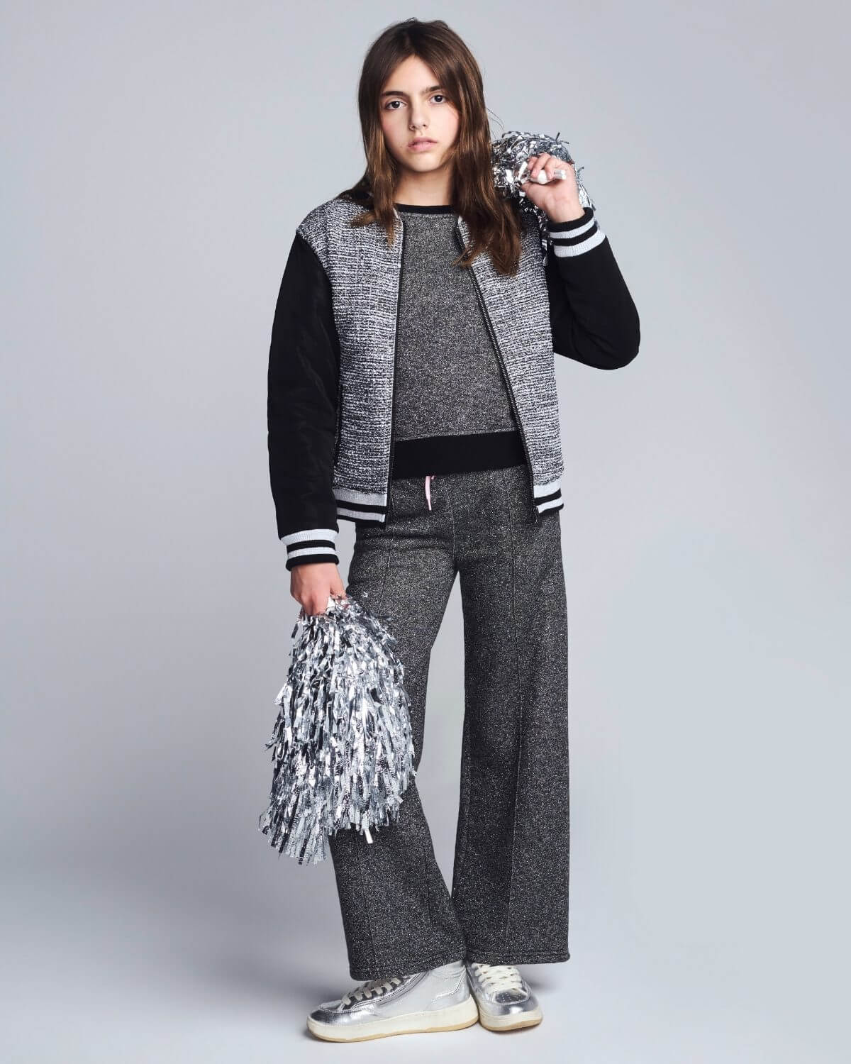 Person wearing a gray and black outfit with pom-poms on a white background