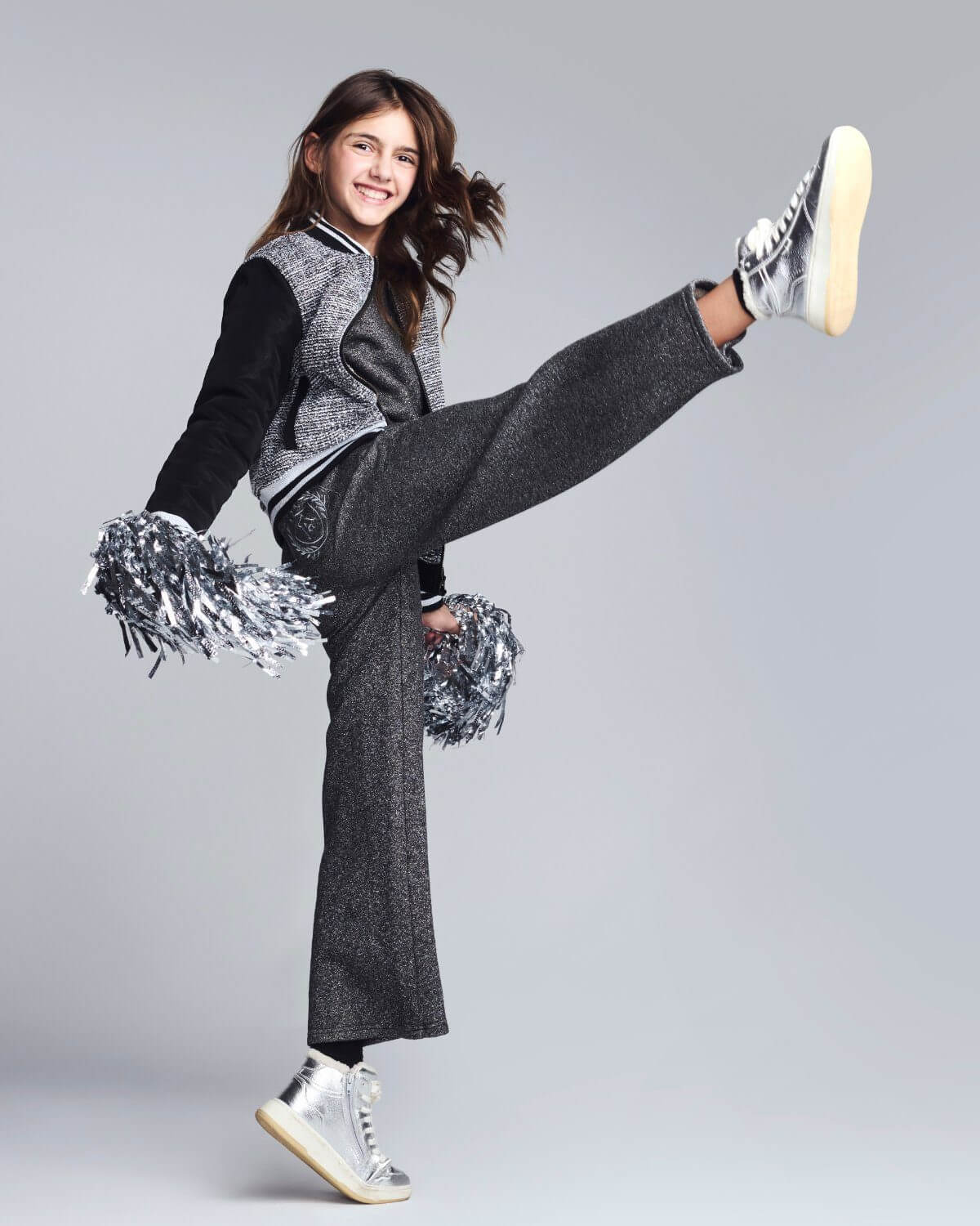 Person in gray outfit with pom-poms on a plain background