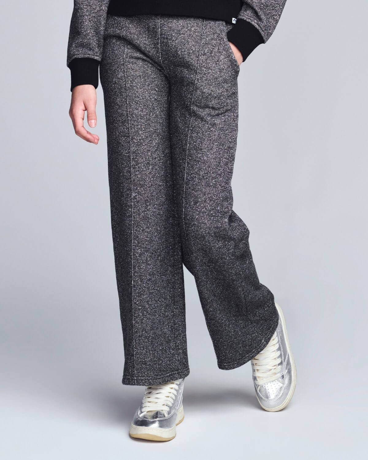 Person wearing gray wide-leg pants with a plain background
