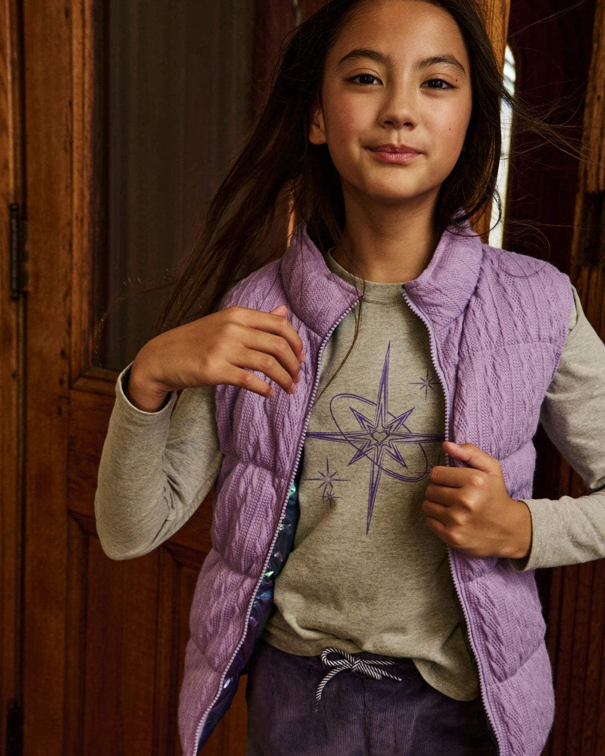 A girl wearing an iridescent purple puffer vest. Appaman Fall/Winter 2026 collection.