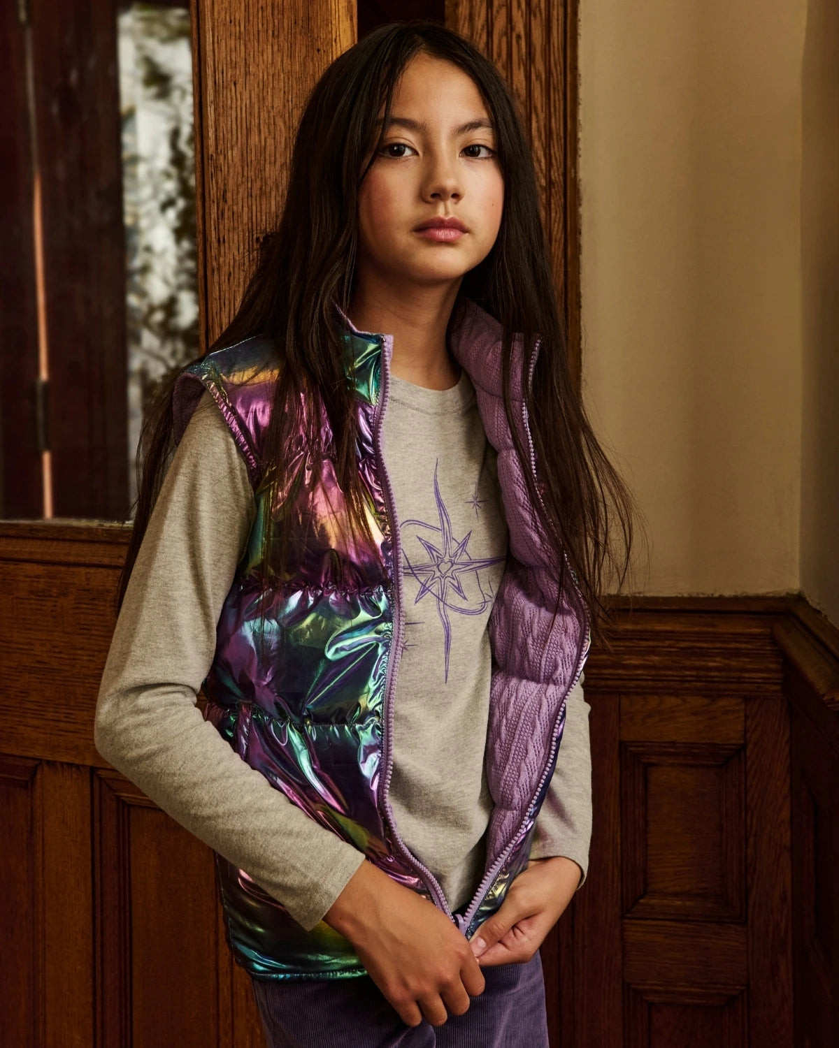 A girl wearing a lavender puffer vest, standing on a staircase. Appaman Fall/Winter 2026 collection.