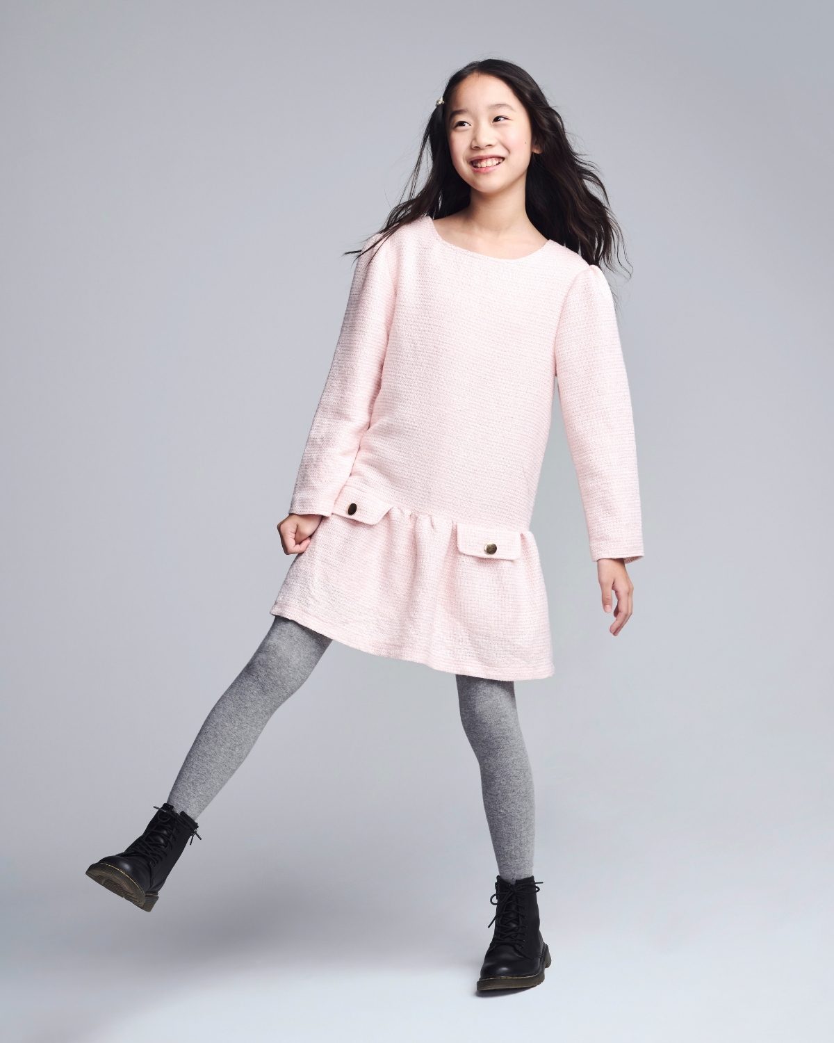 Young girl wearing a light pink coat on a gray background