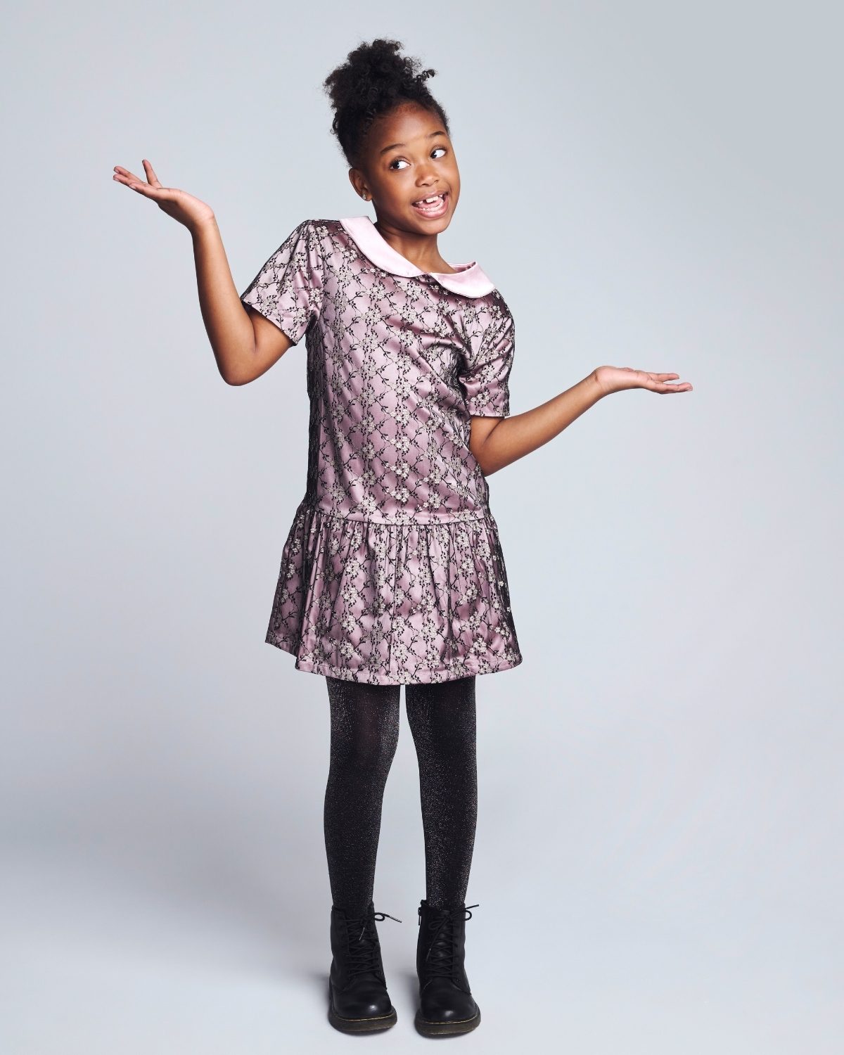 Young girl wearing a floral dress with a white collar against a plain background