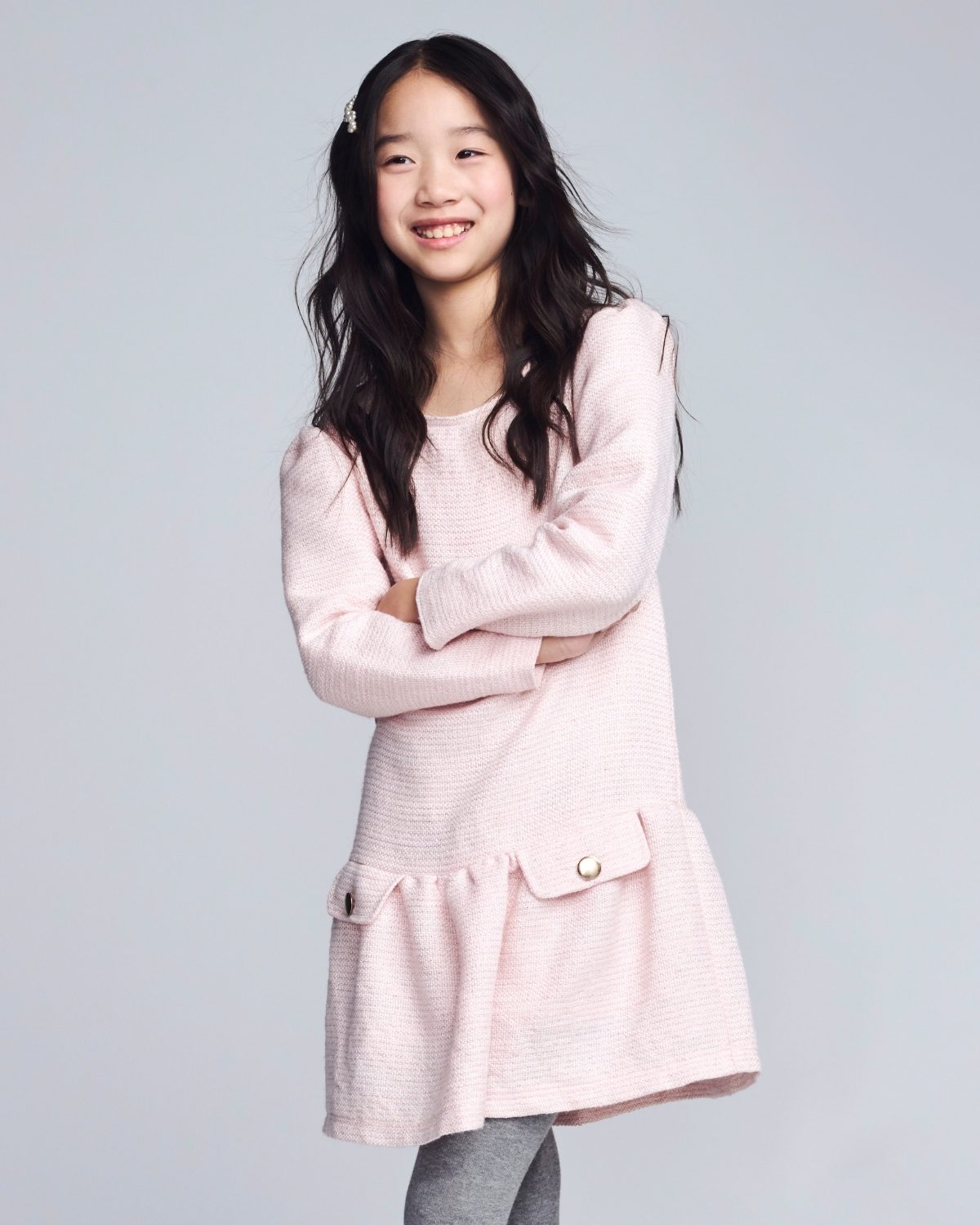 Young girl wearing a light pink dress with a plain background