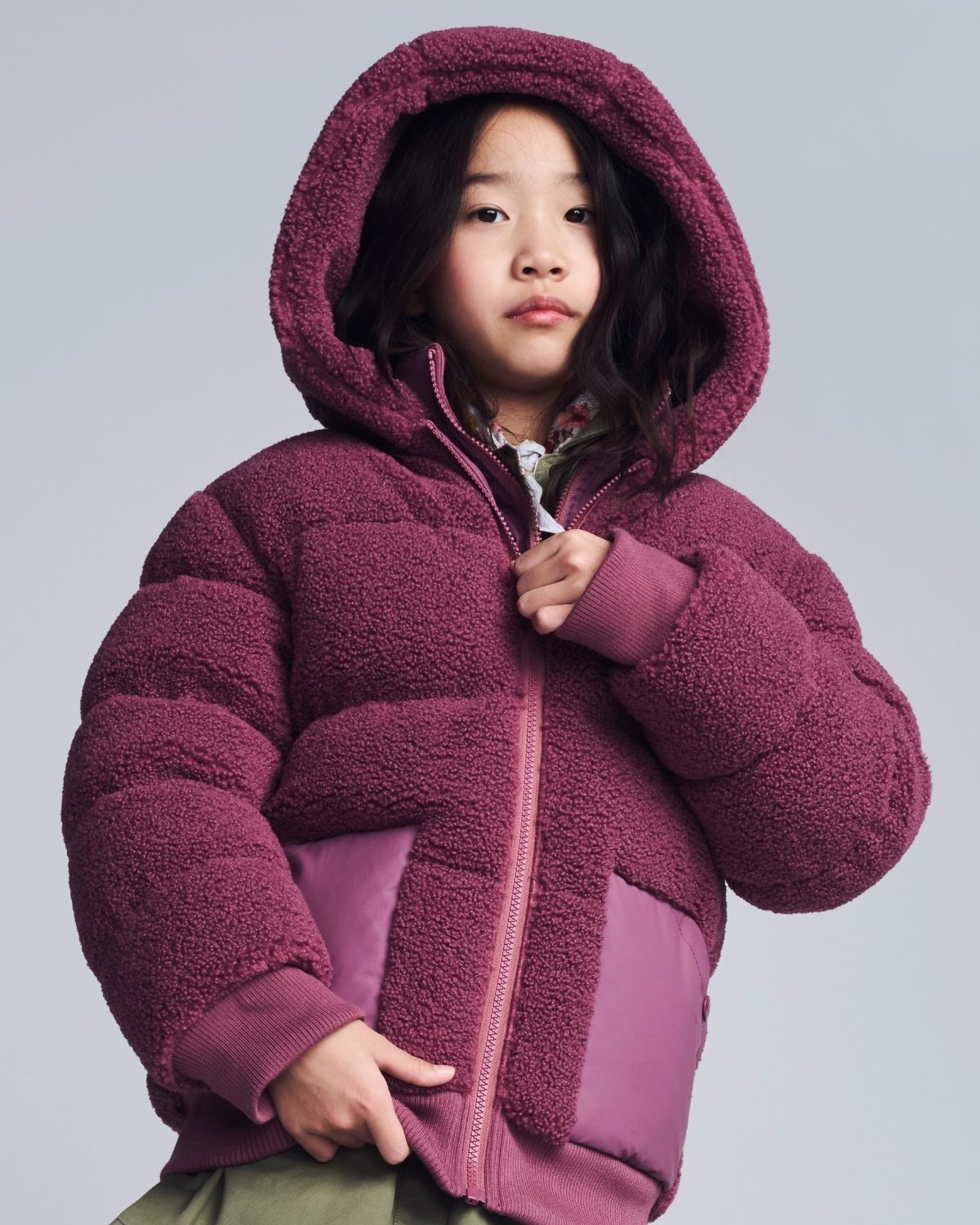 Child wearing a purple fleece jacket on a gray background