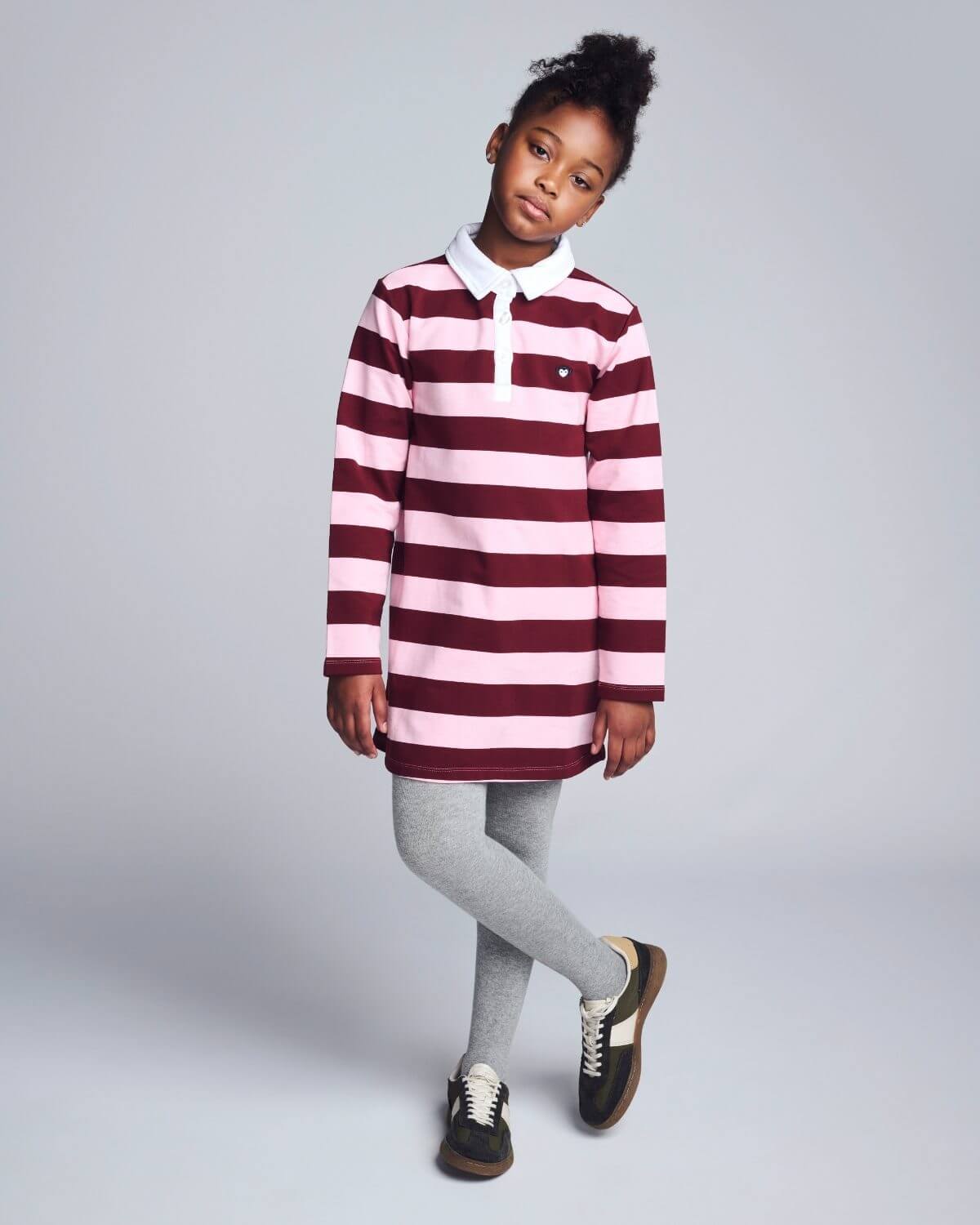 Child wearing a red and white striped rugby shirt on a gray background