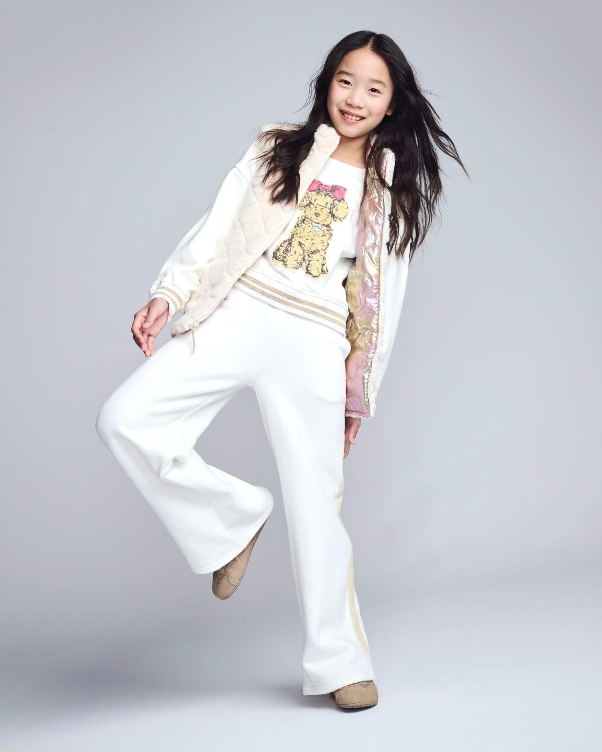 Young girl in a white outfit with a teddy bear design on a gray background