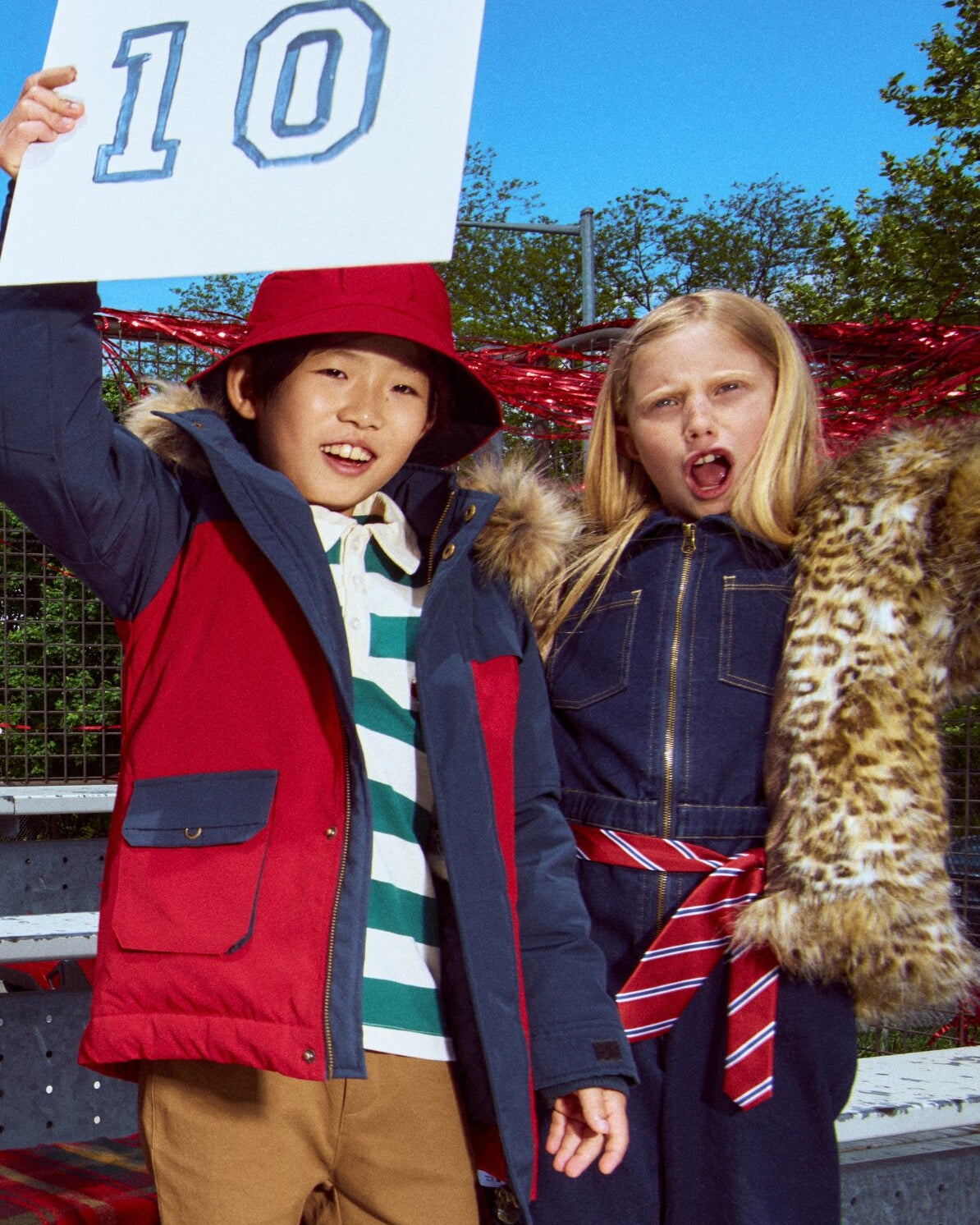 Two children in winter clothing with a child holding up a number 10 sign.