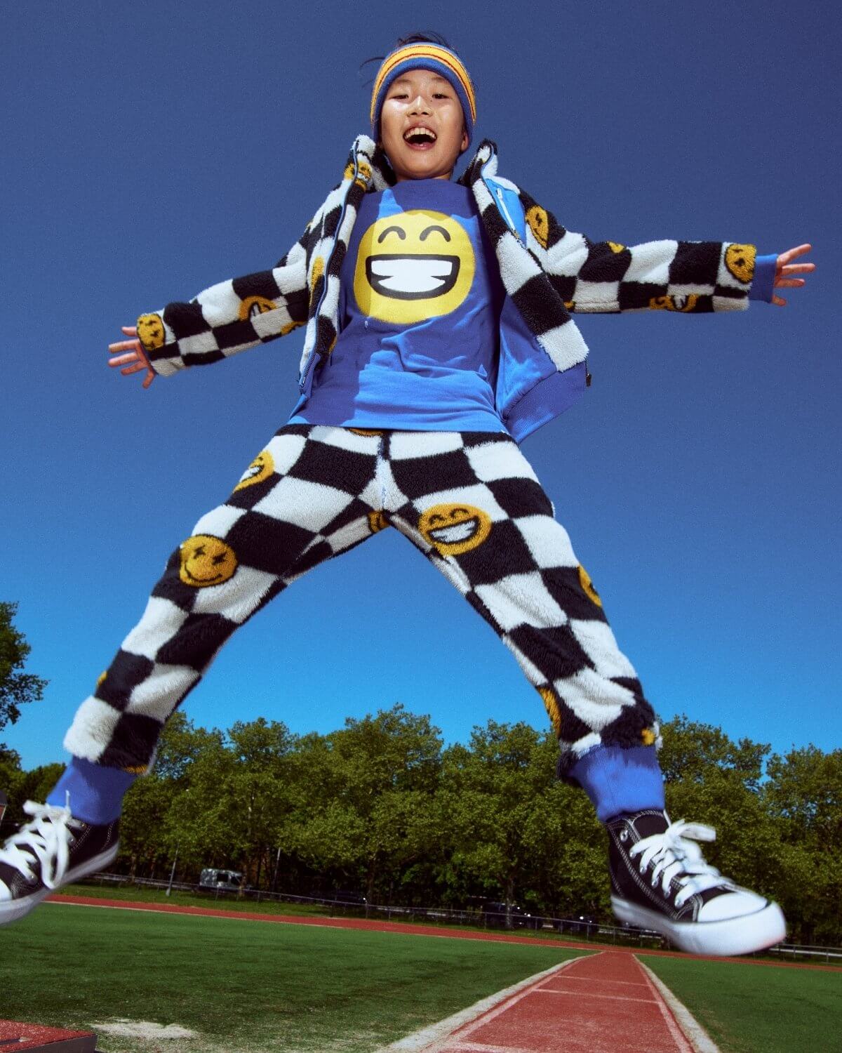 Child in a colorful outfit with smiley face patterns on a sports field
