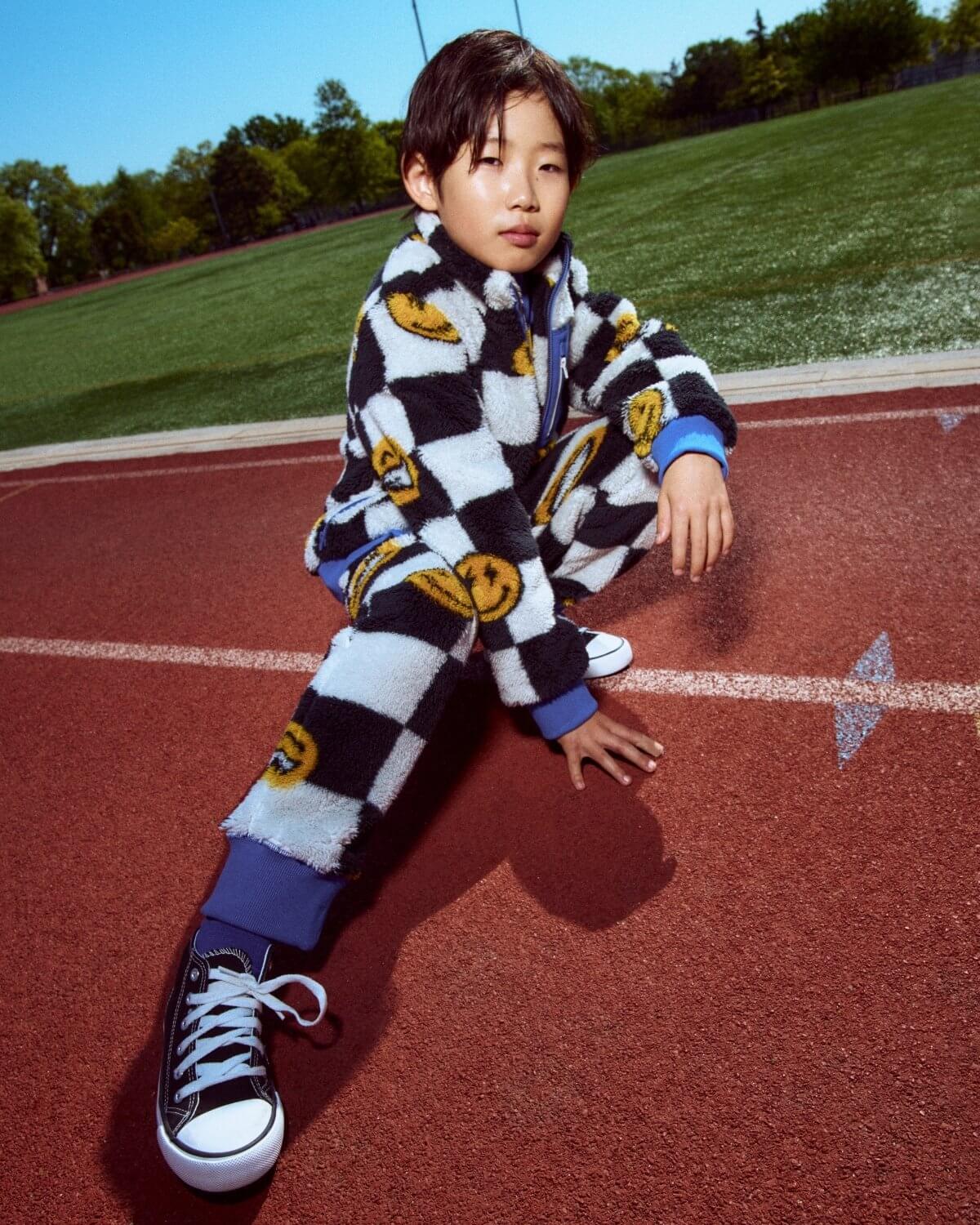 Person wearing a checkered outfit with cartoon character design on a track