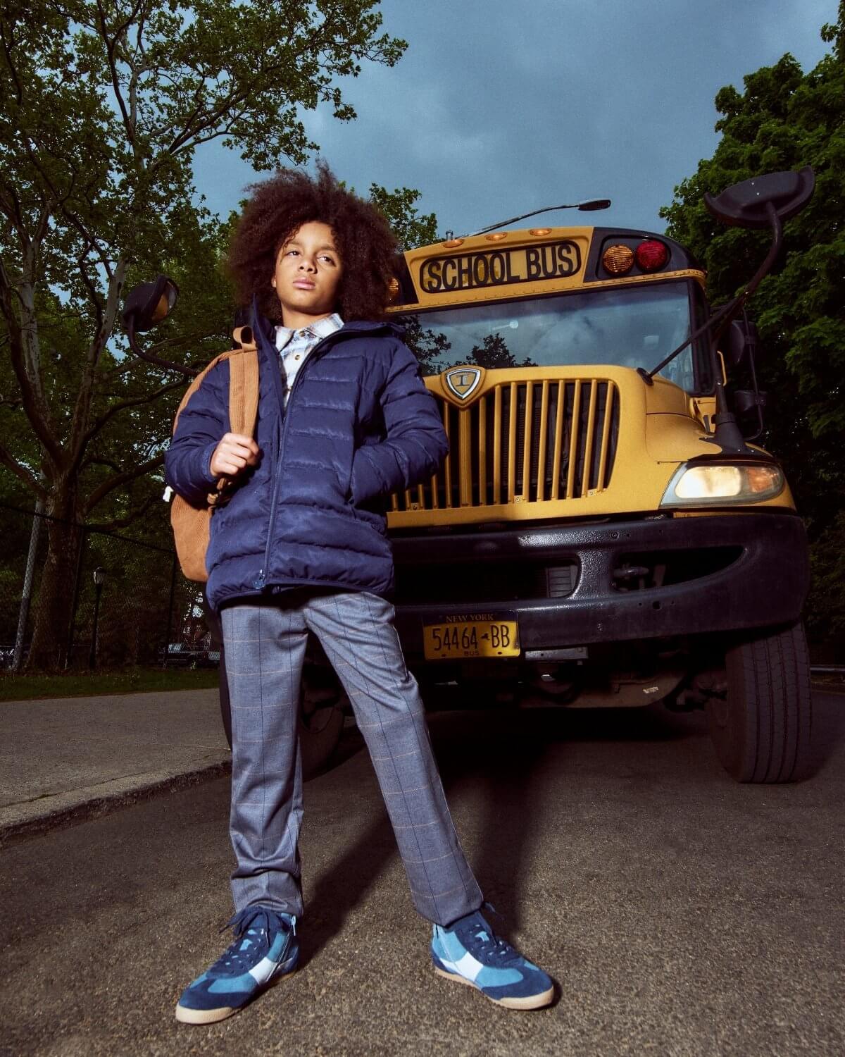 Person standing in front of a school bus with a backpack