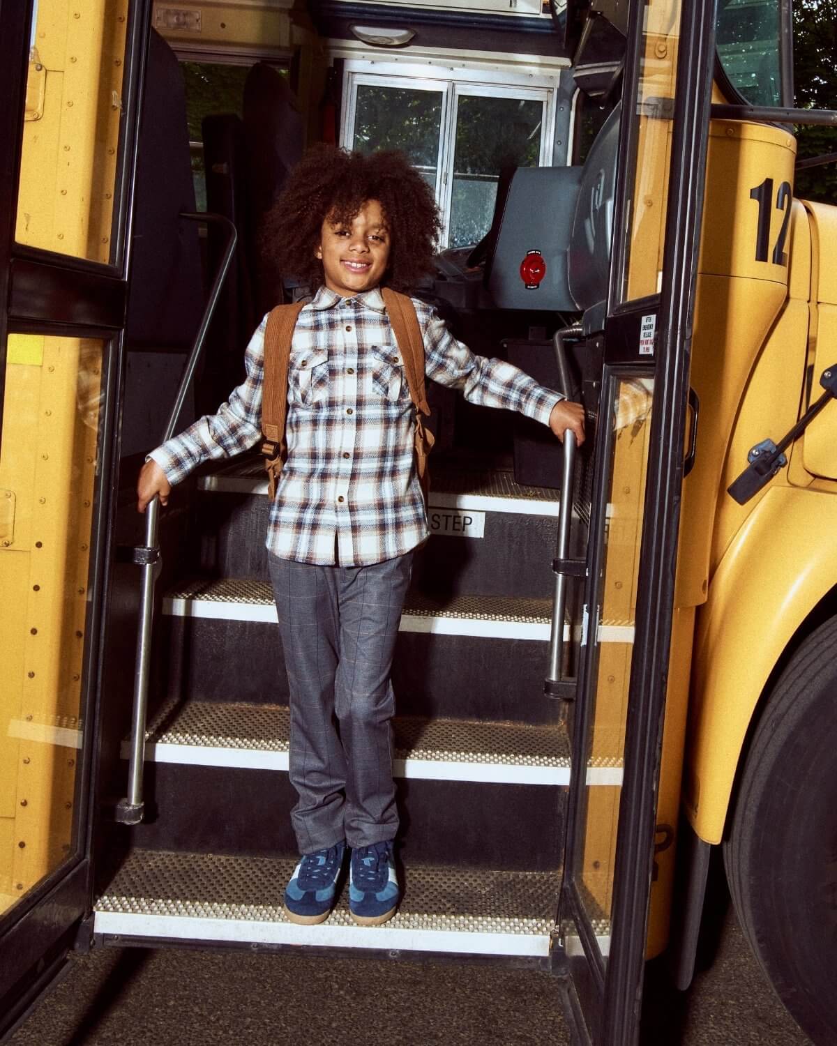 Child standing on the steps of a yellow school bus