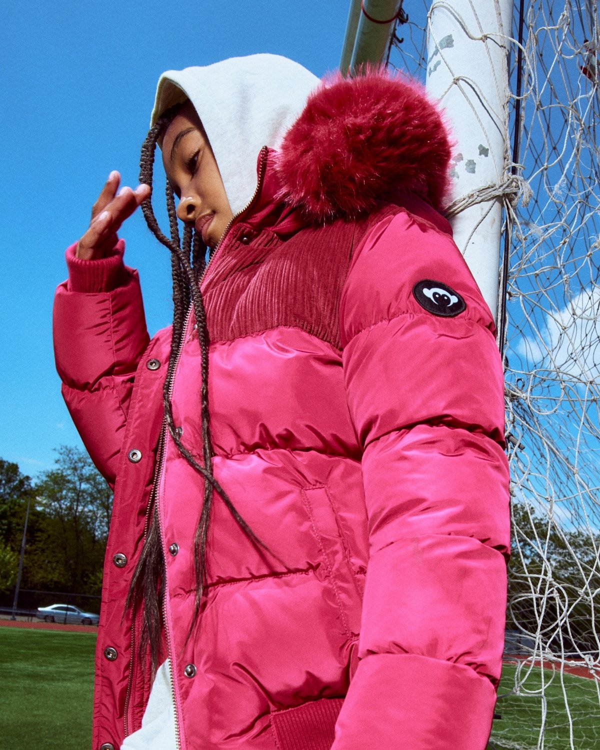 Person wearing a pink puffer jacket with a hood in an outdoor setting