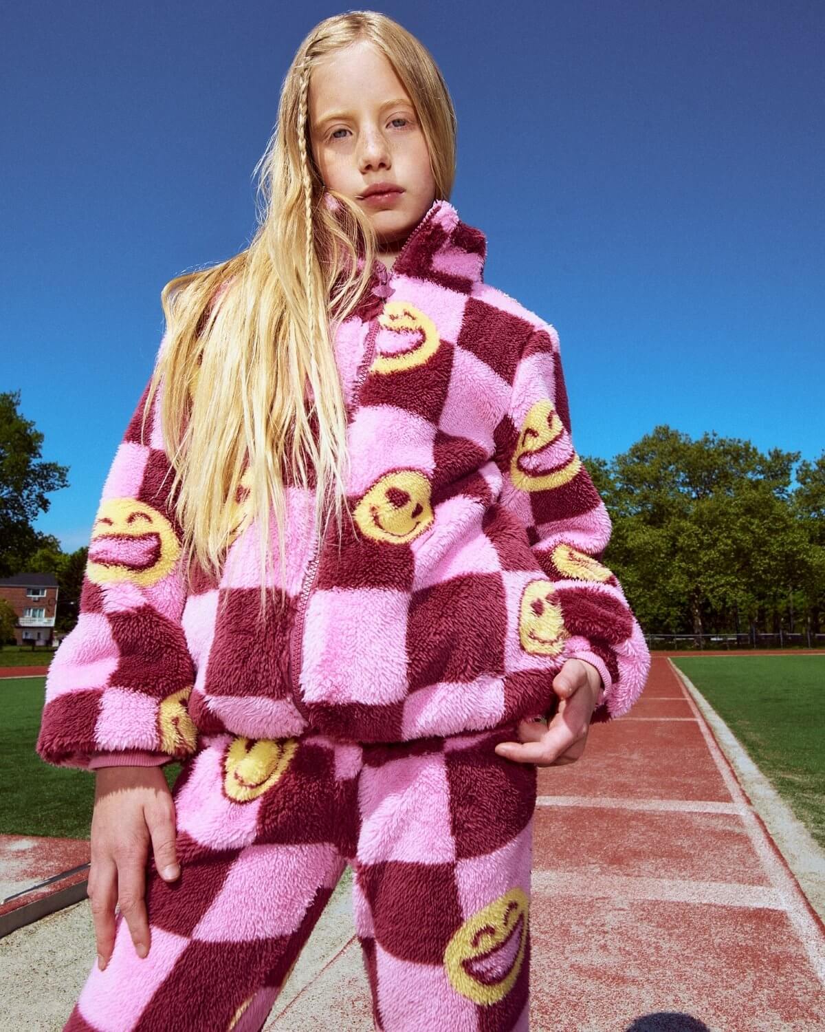 Person wearing a pink and red checkered outfit with smiley face patterns on a track.