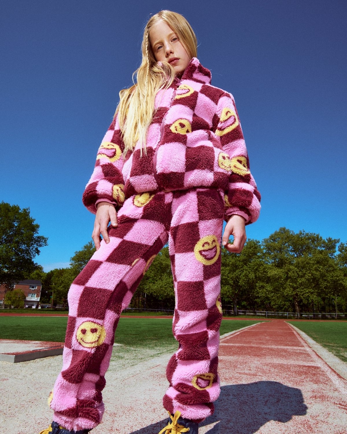 Person wearing a pink and red checkered outfit with smiley face designs on a track.
