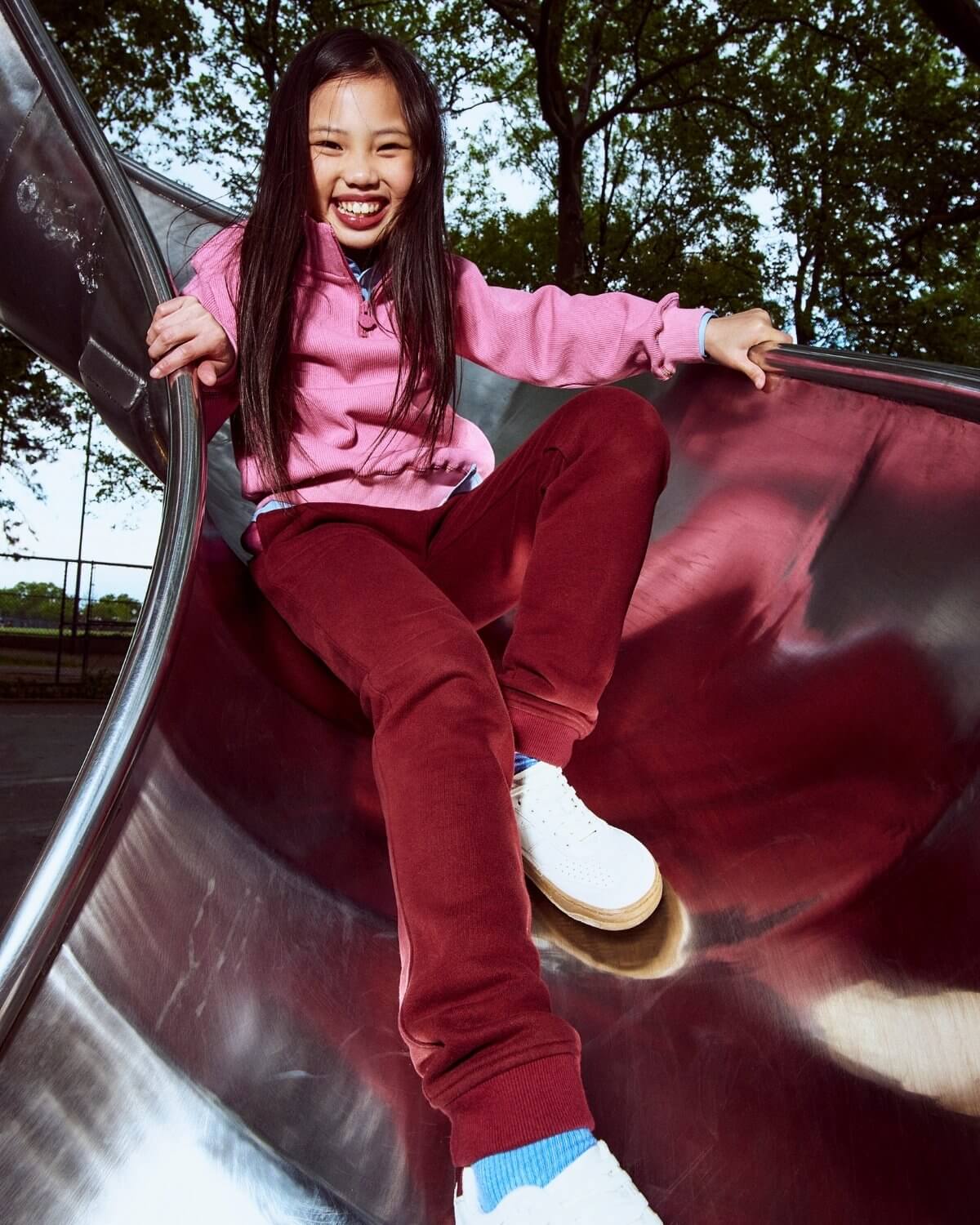 Child sliding down a playground slide with trees in the background