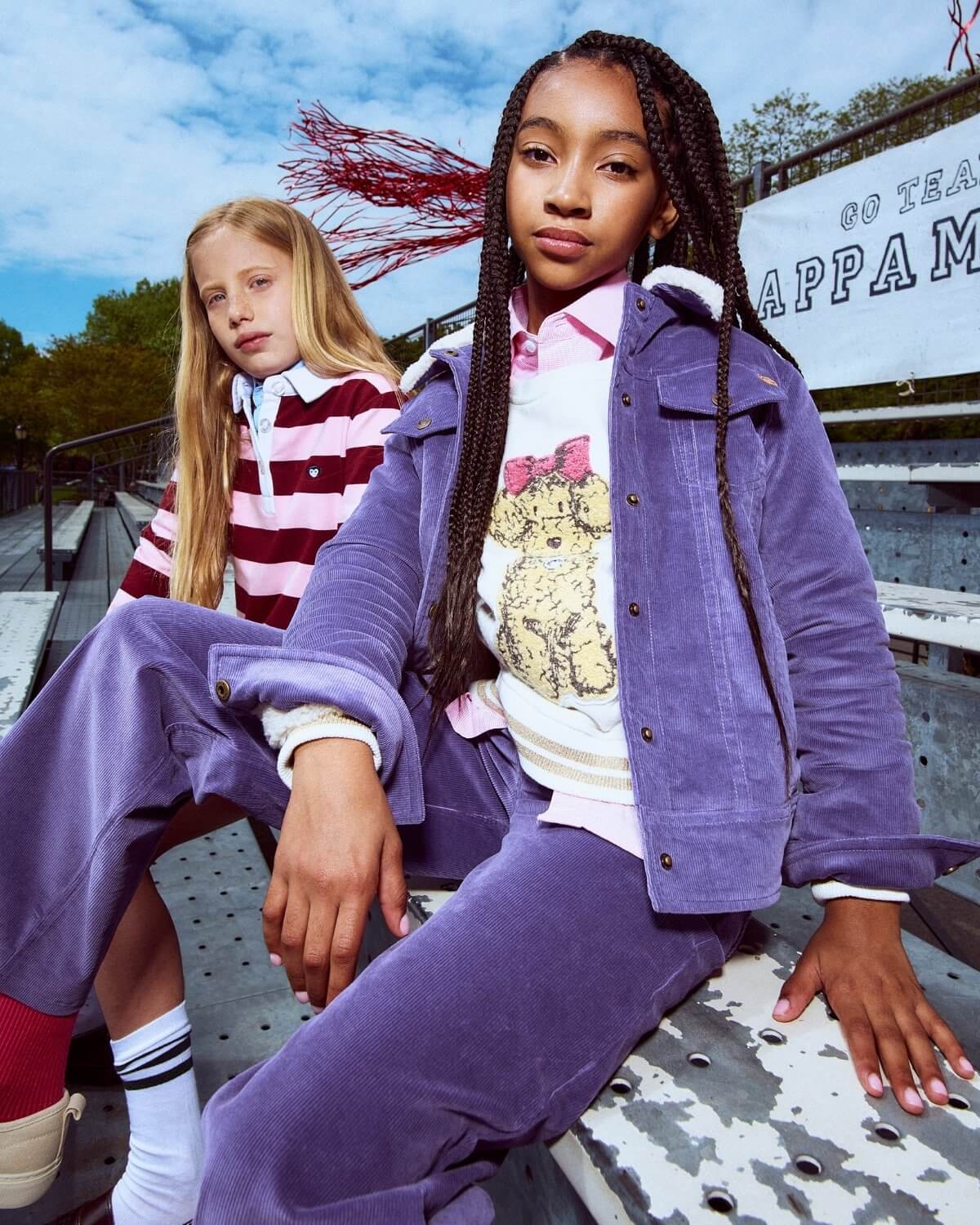 Two young girls sitting on a bench with a colorful background