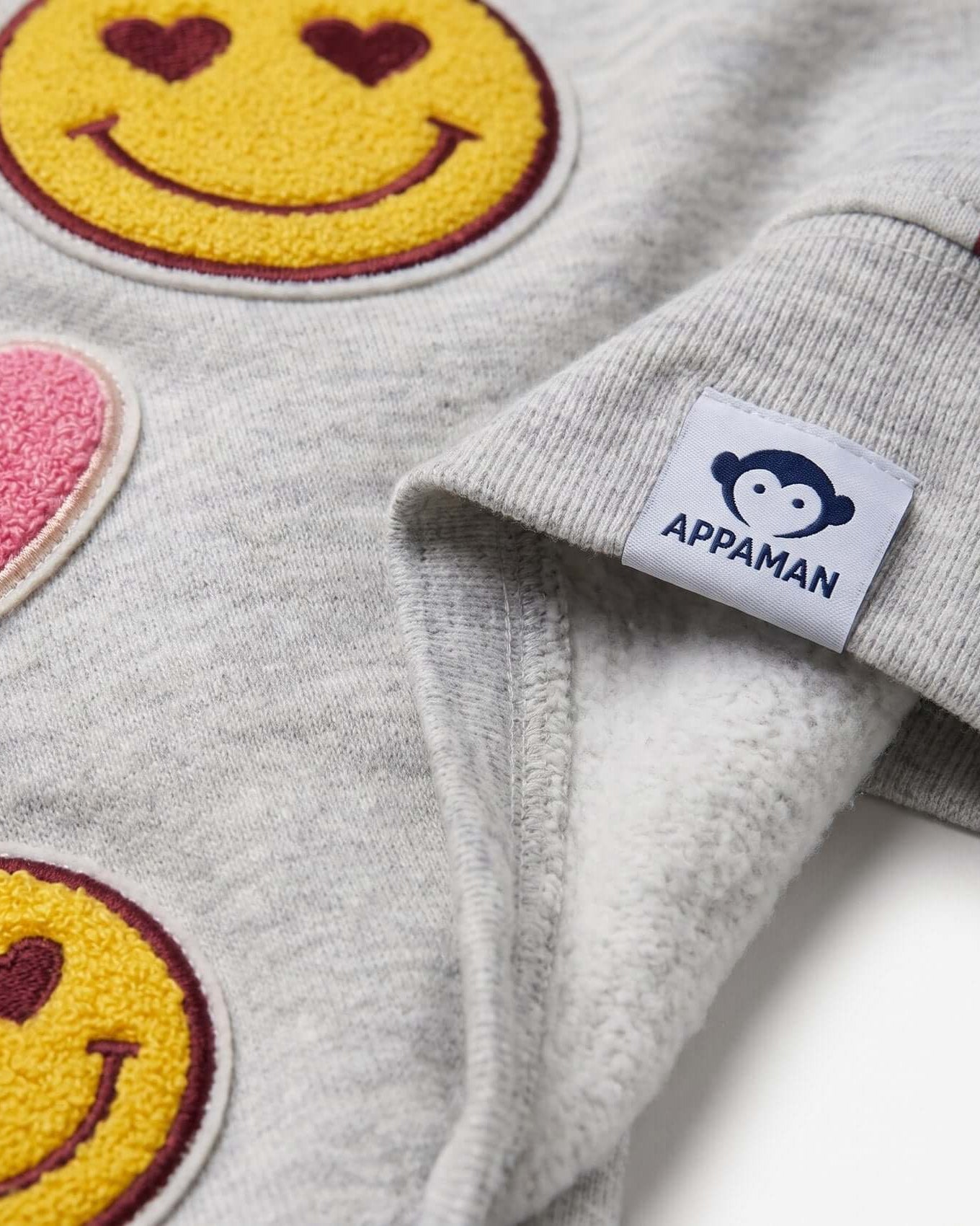 Gray fleece jacket with smiley face patches and Appaman label