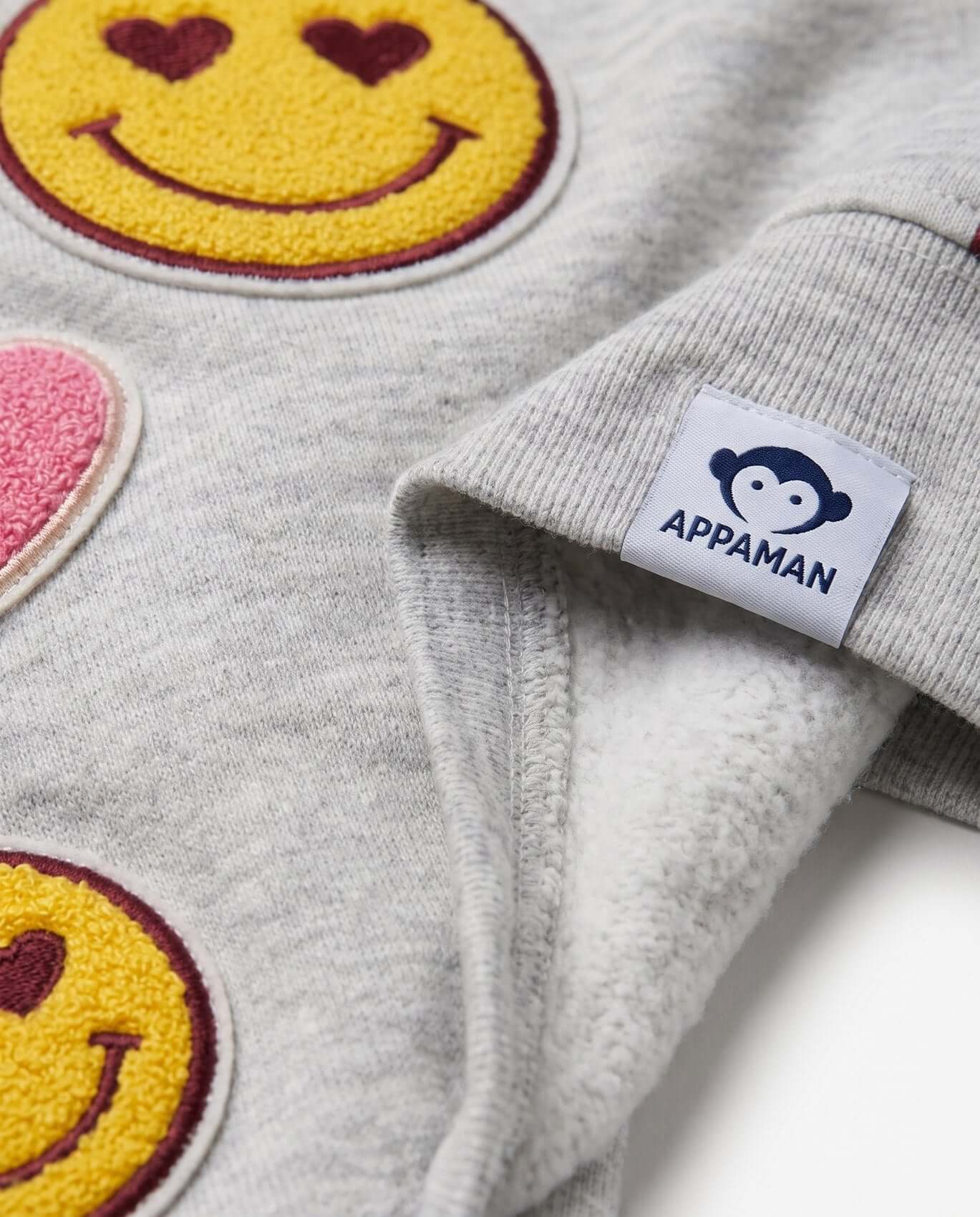 Gray fleece jacket with smiley face patches and Appaman label