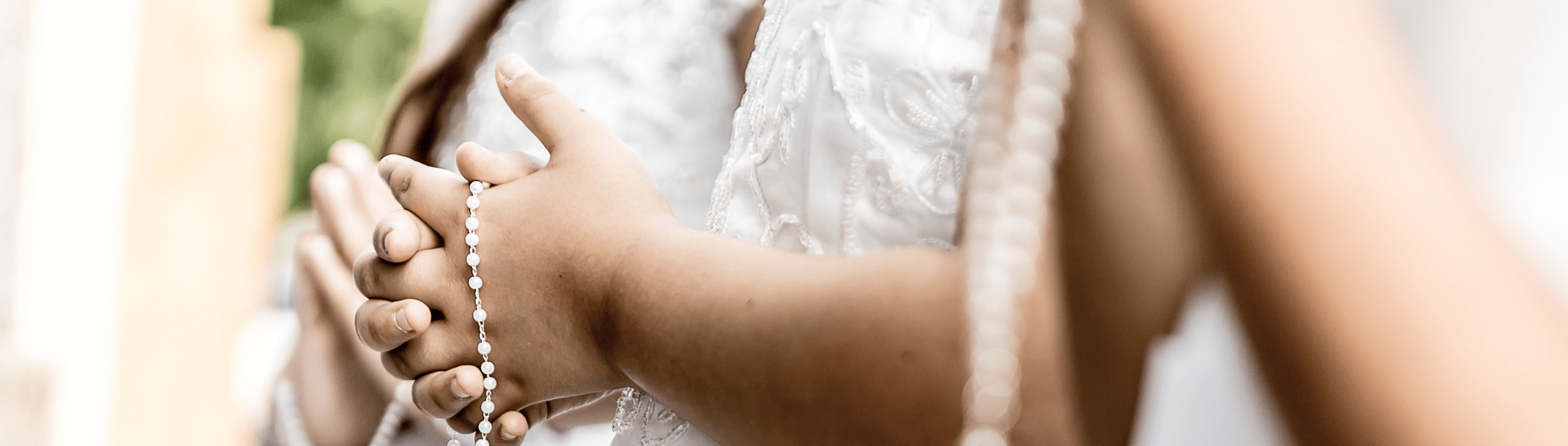 Close-up of a young girl’s hands holding a rosary, showcasing elegance for a First Communion outfit.