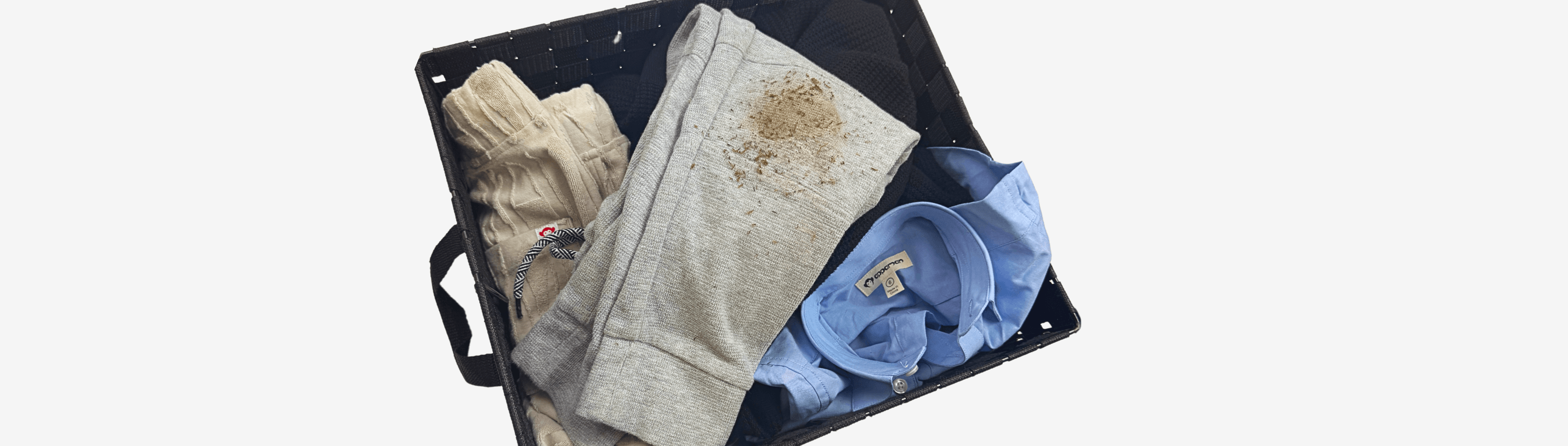 A laundry basket filled with kids' clothes showing dirt stains, highlighting the playful adventures of childhood.