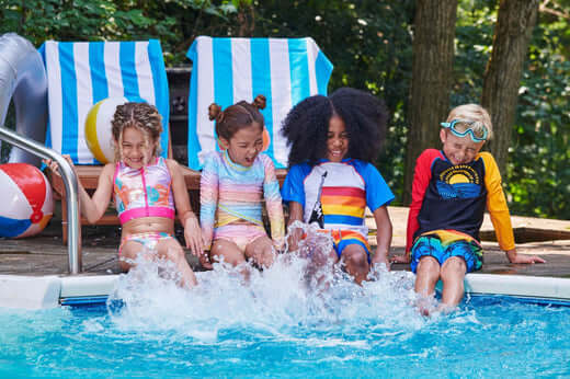 Four stylish kids splashing in a pool, showcasing fun summer swimwear and vibrant beach vibes.