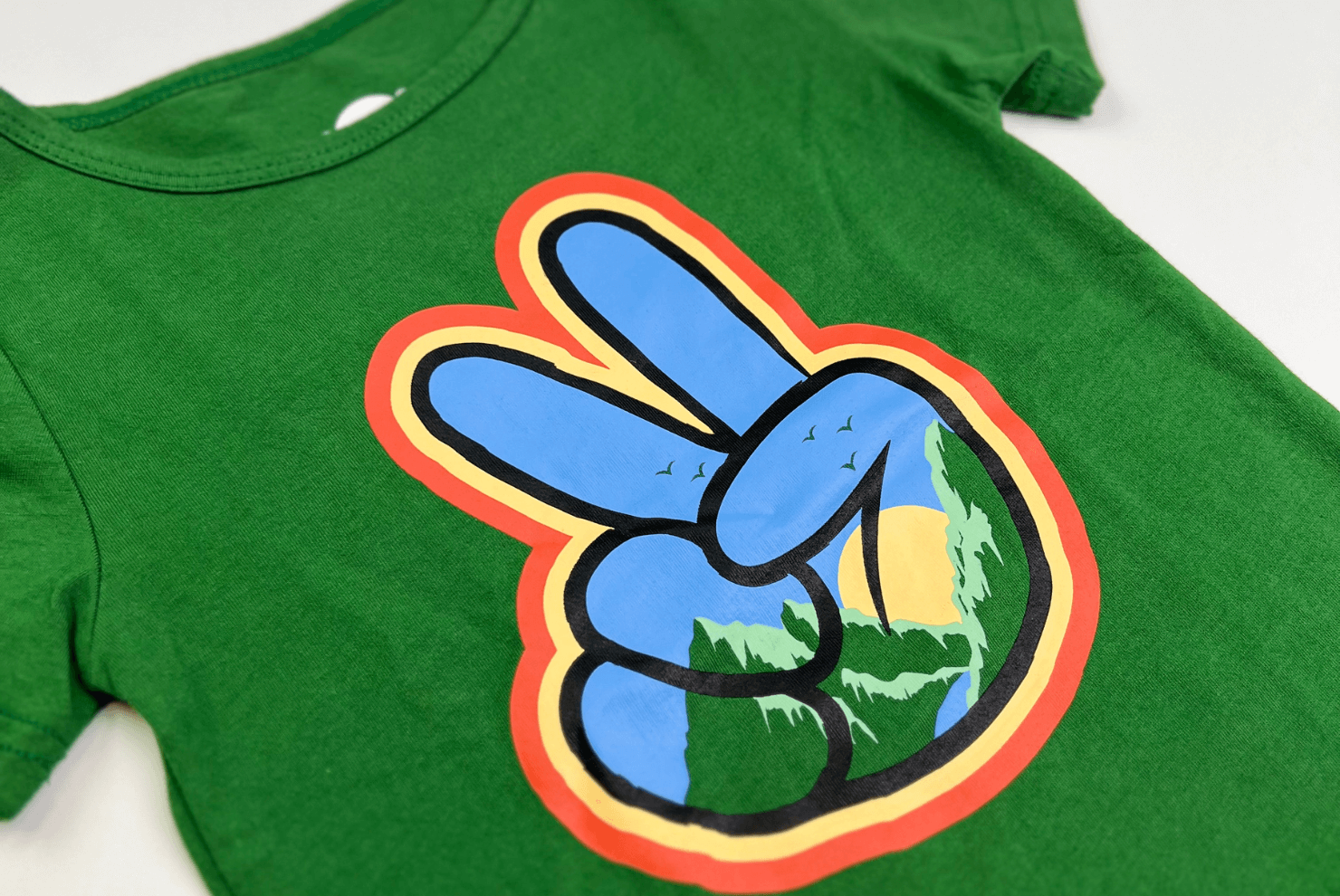 Green kids' t-shirt featuring a peace sign design with nature imagery for Earth Day celebrations.