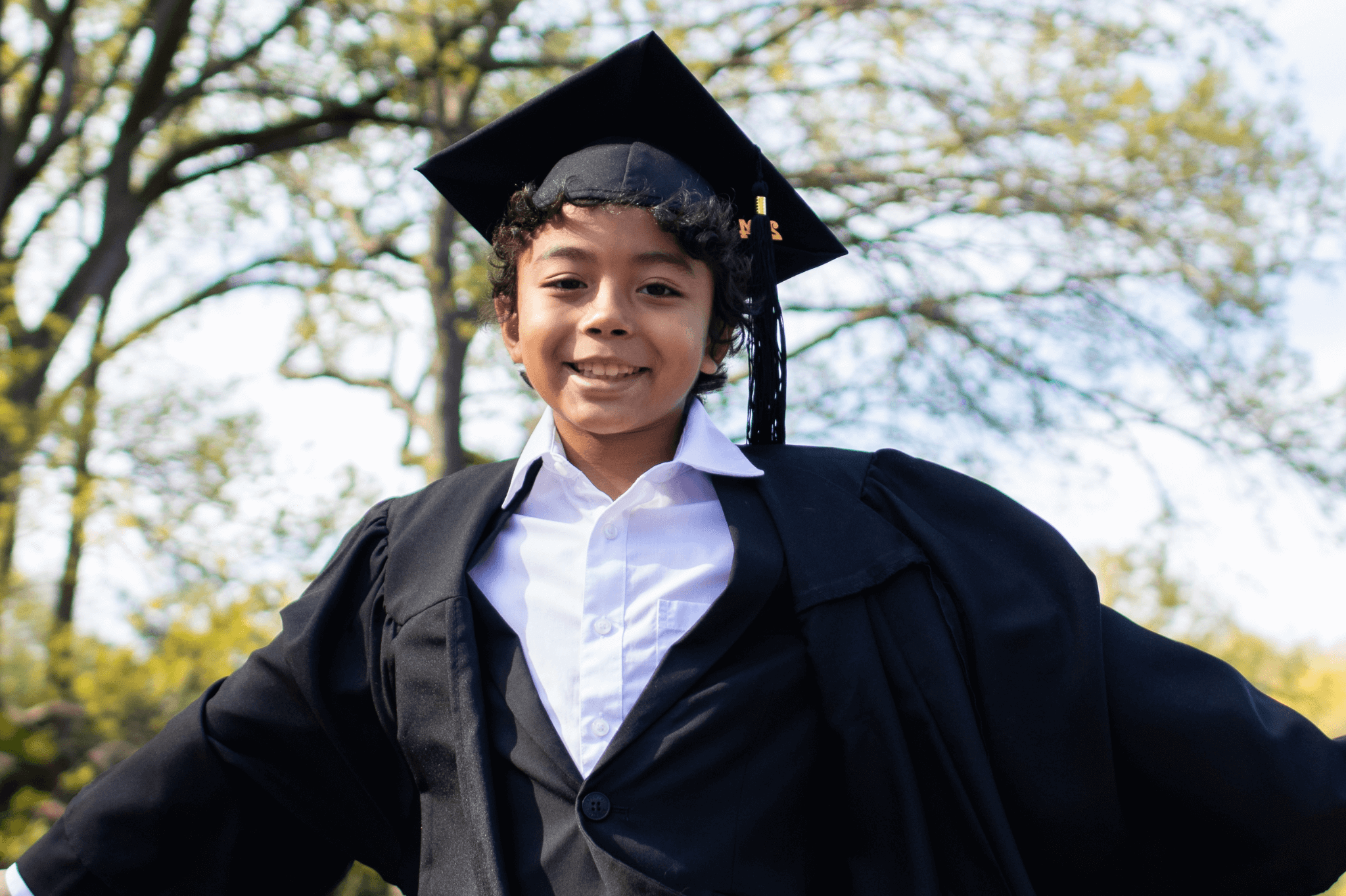 Celebrating preschool graduation: A joyful boy in cap and gown, ready to take on new adventures in style.