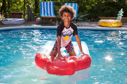 Boy in stylish swimwear having fun on a float in the pool—perfect for summer adventures and family fun!