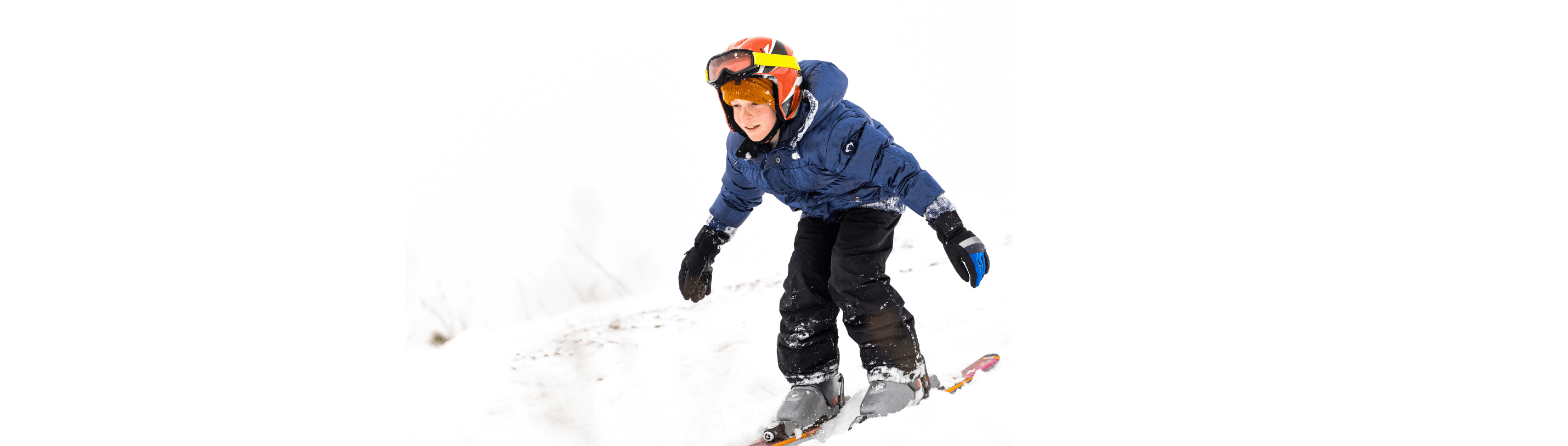 A joyful child skiing down a snowy slope, showcasing the thrill of family winter adventures.