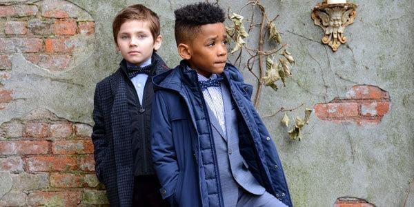Two stylish boys showcase modern outerwear and tailored looks, perfect for kids’ fashion and striking a confident pose.