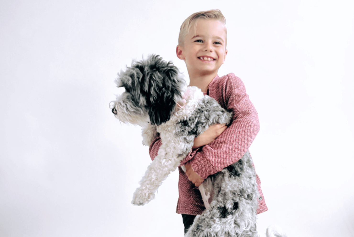 Joyful boy holding his fluffy dog, showcasing a fun moment of friendship and playfulness.