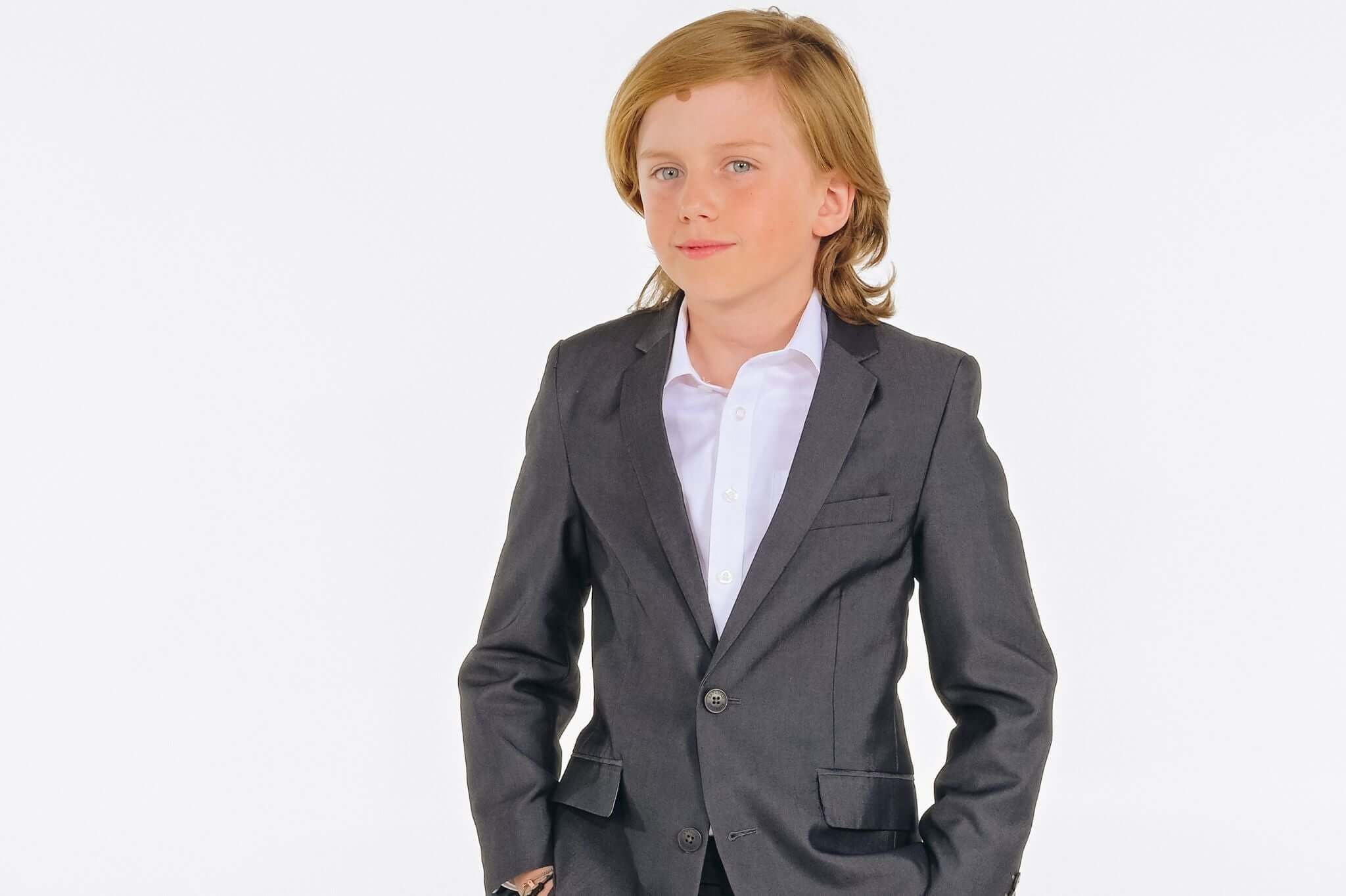 Stylish boy in a dark suit, ready for First Communion—capturing elegance and modern flair for kids' fashion.